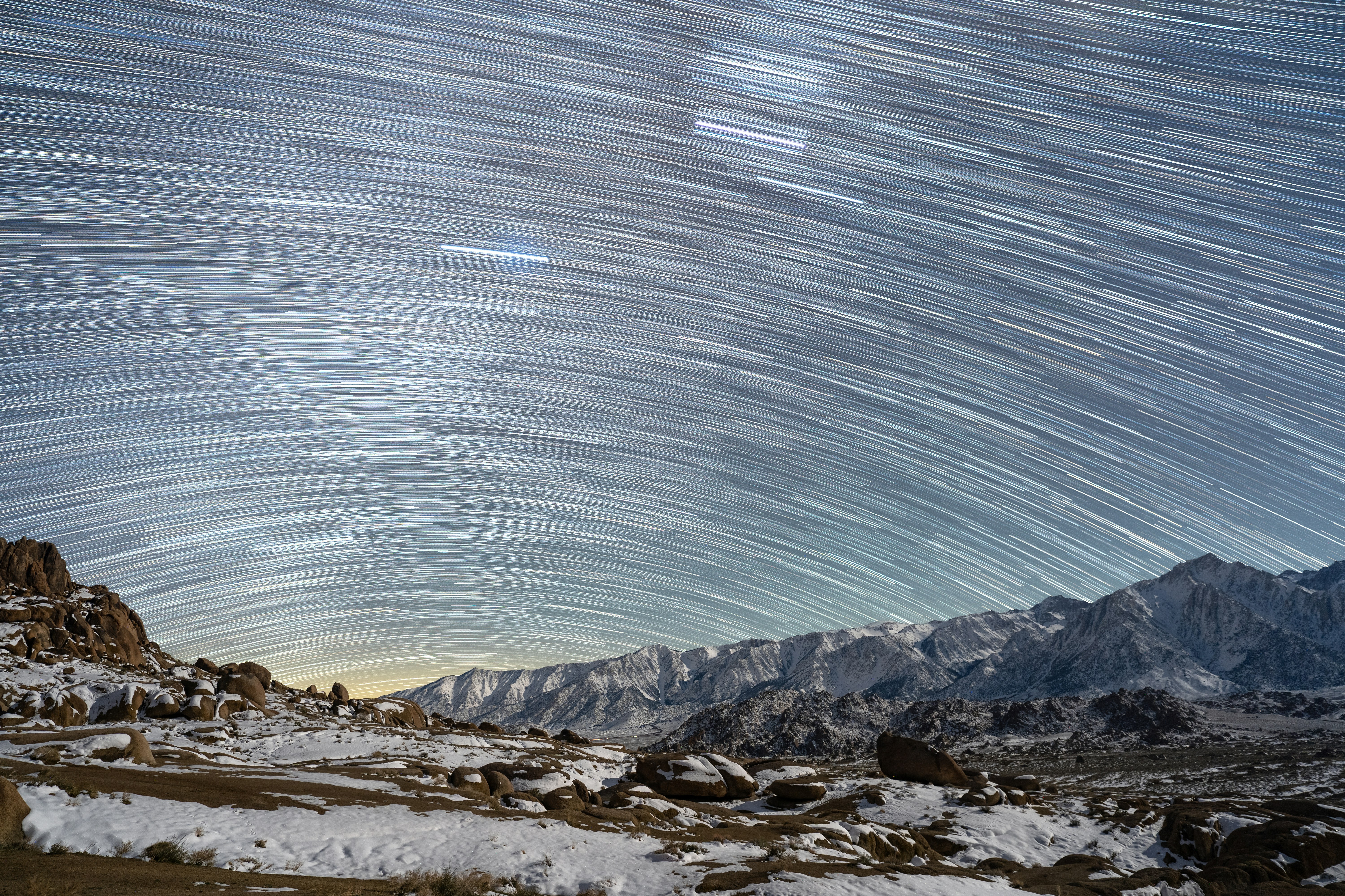 Star trails over snow-covered mountains at night