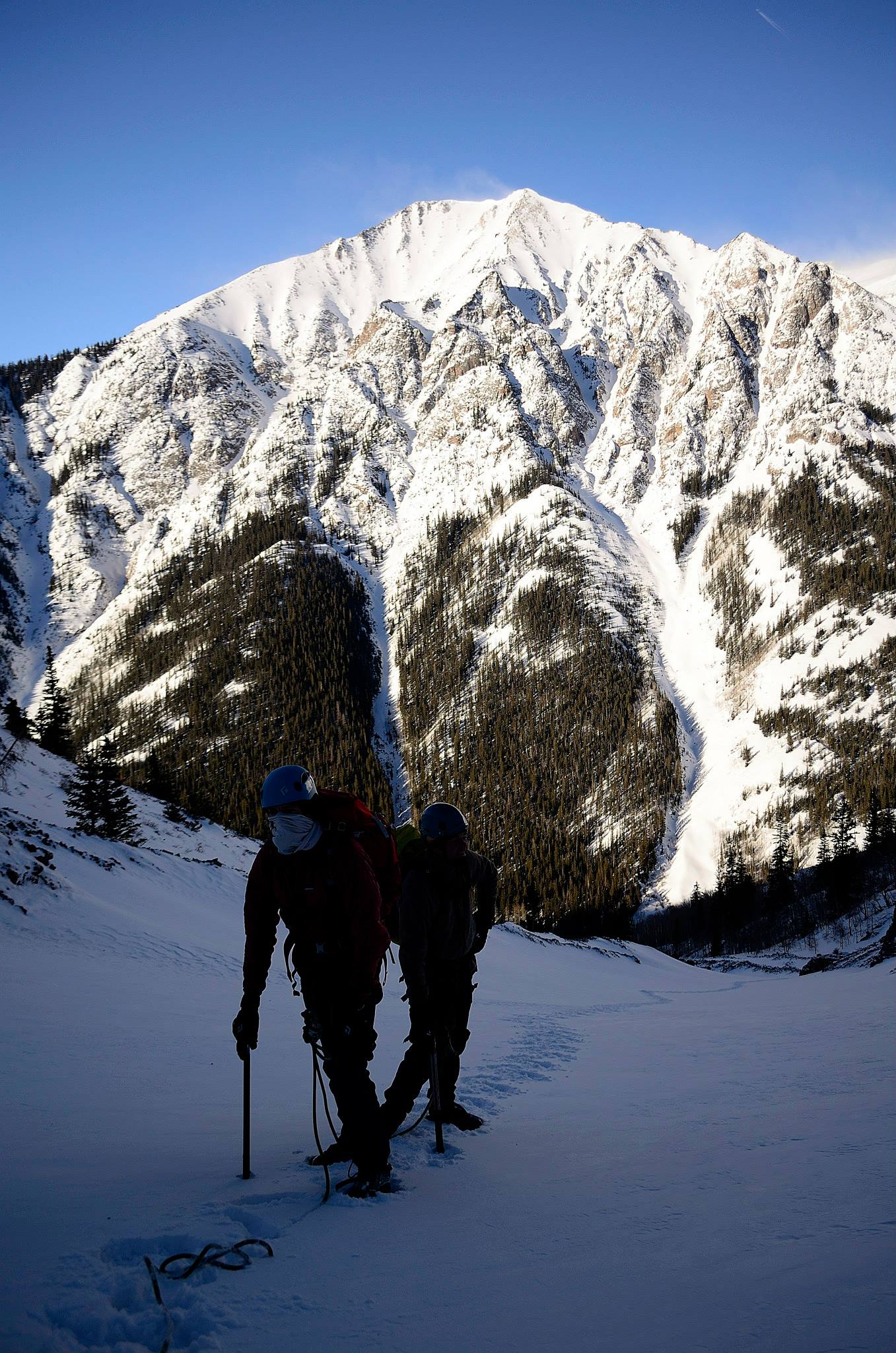 Climbers rest on snow slope with 13er in the background