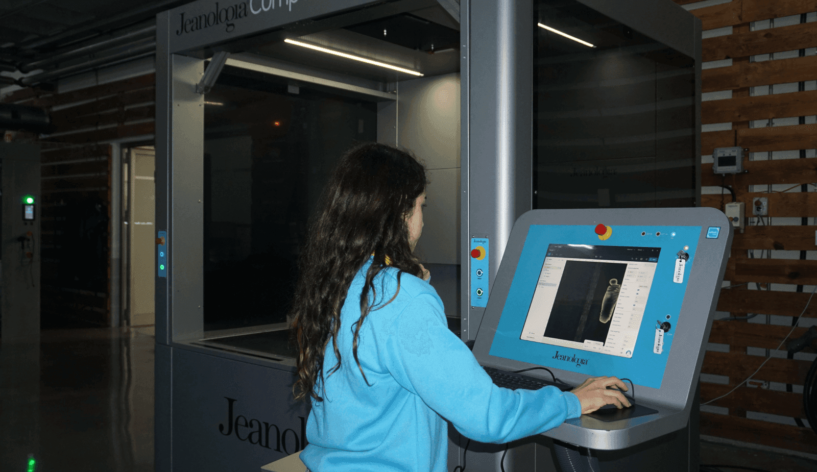 Operator of Jeanologia machine preparing denim garment for laser marking in a factory environment