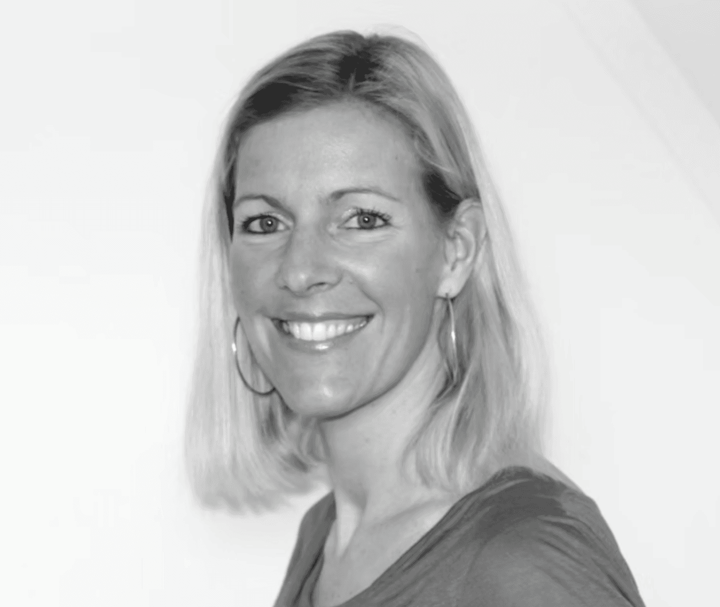 A person with light brown hair in a green blazer and cream turtleneck, set against a neutral background, exuding a composed elegance.