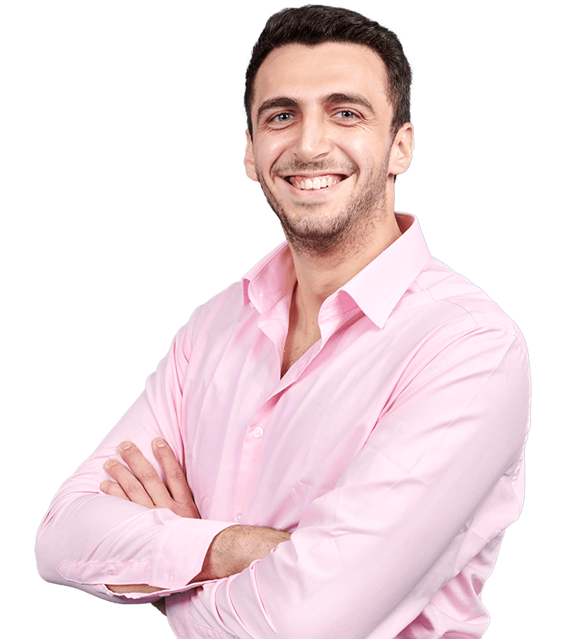 Professional headshot of Hadi Farhat wearing a pale pink shirt with open collar. They have their arms folded in a friendly and relaxed manner. They are smiling broadly.