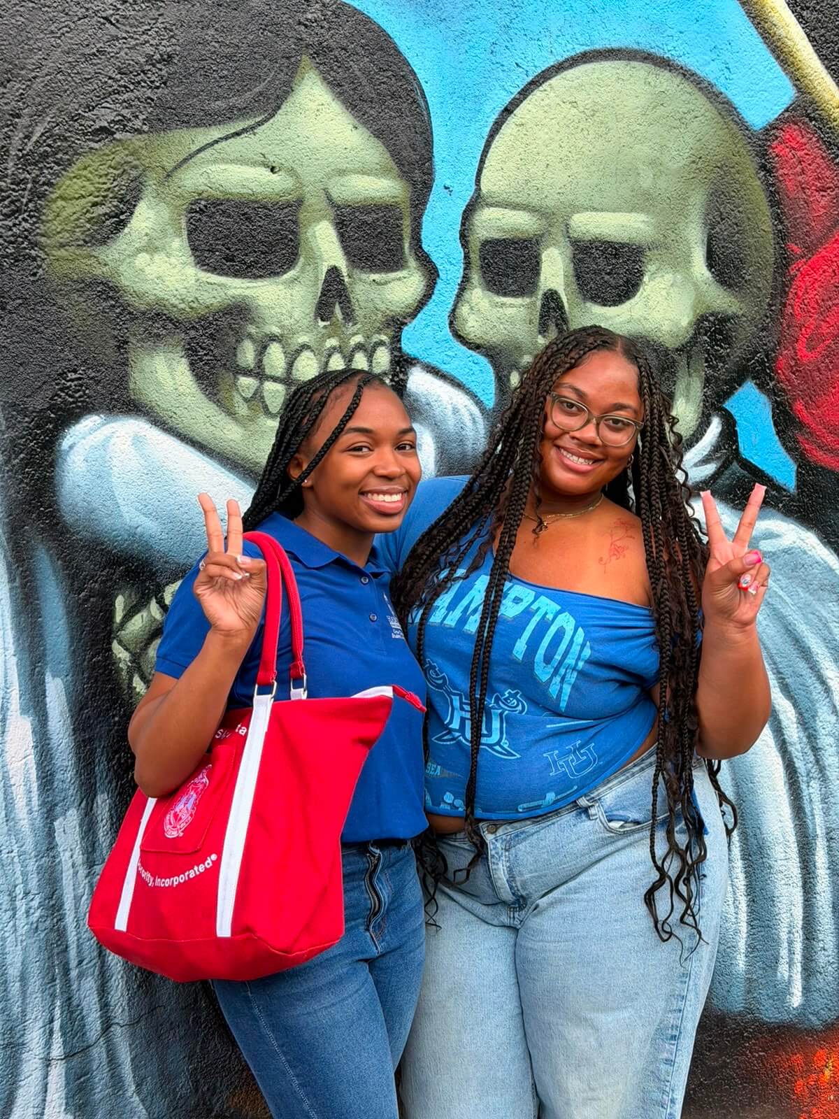2 Hampton students pose in front of a mural.