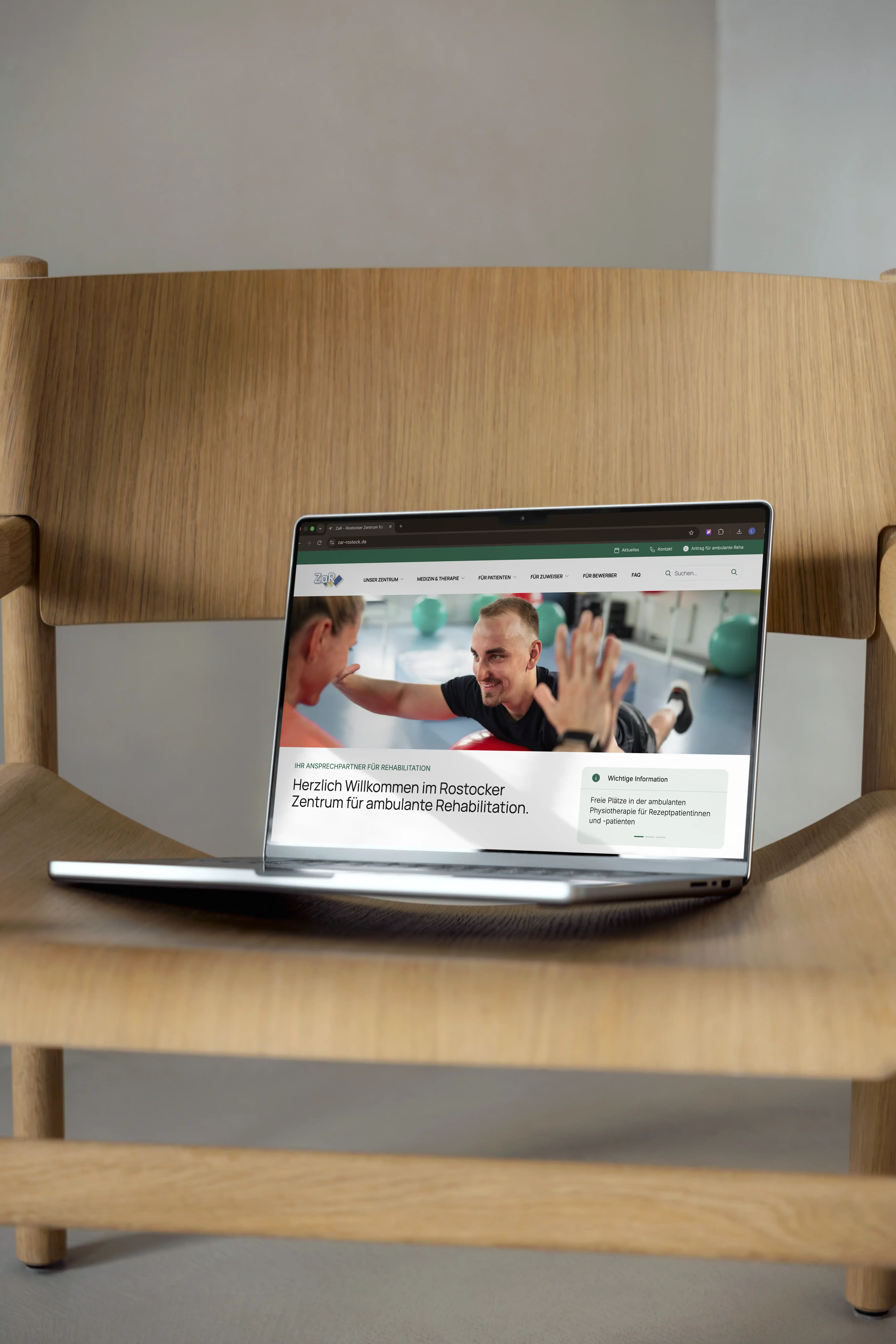 A laptop sits on a wooden surface, displaying a cheerful image of people on its screen.