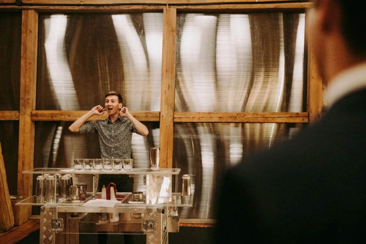 Barman na weselu pokazuje sztuczki barmańskie przed zgromadzonymi gośćmi podczas pokazu barmańskiego