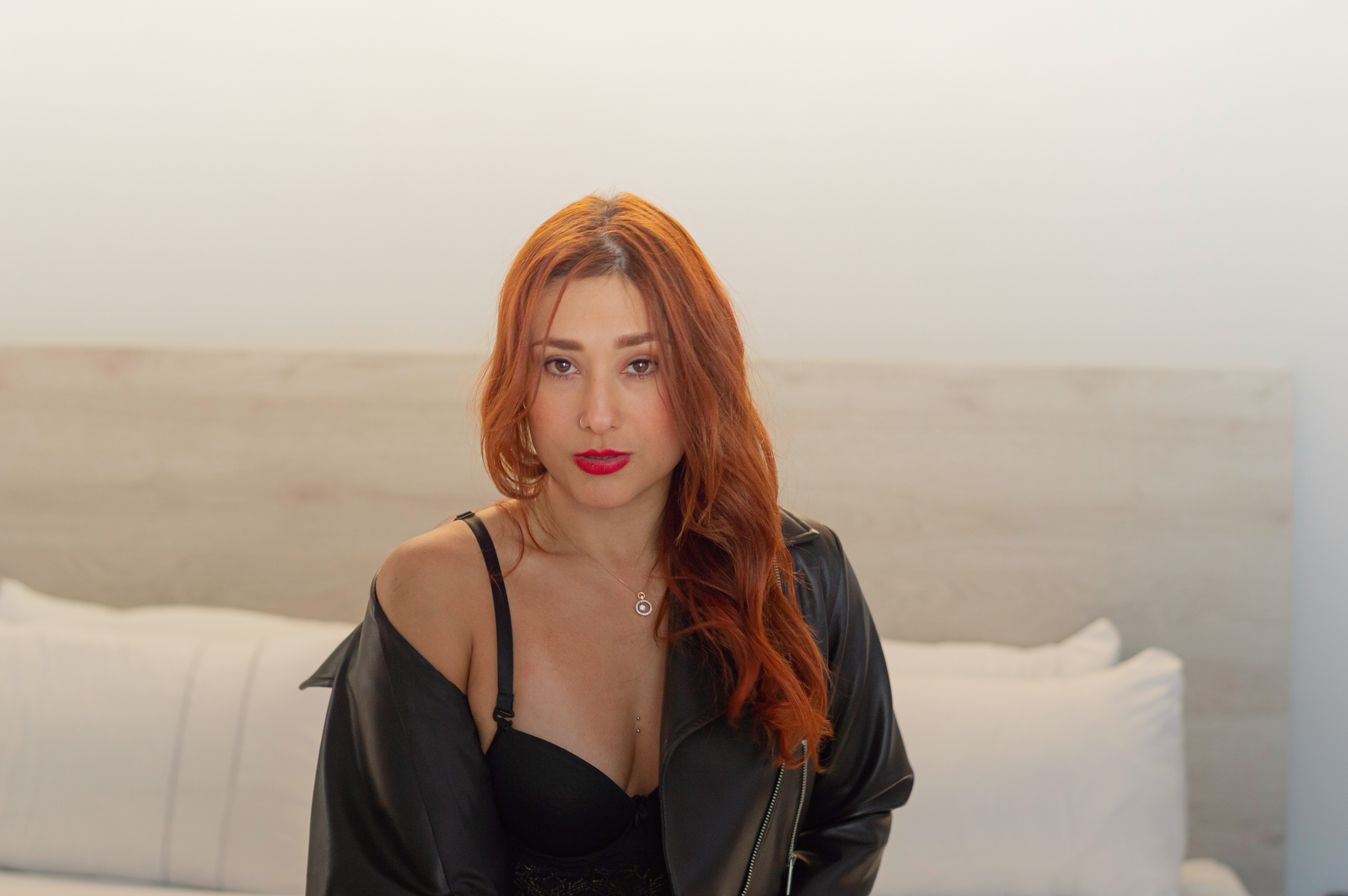 Woman with red hair wearing a black jacket and lingerie.