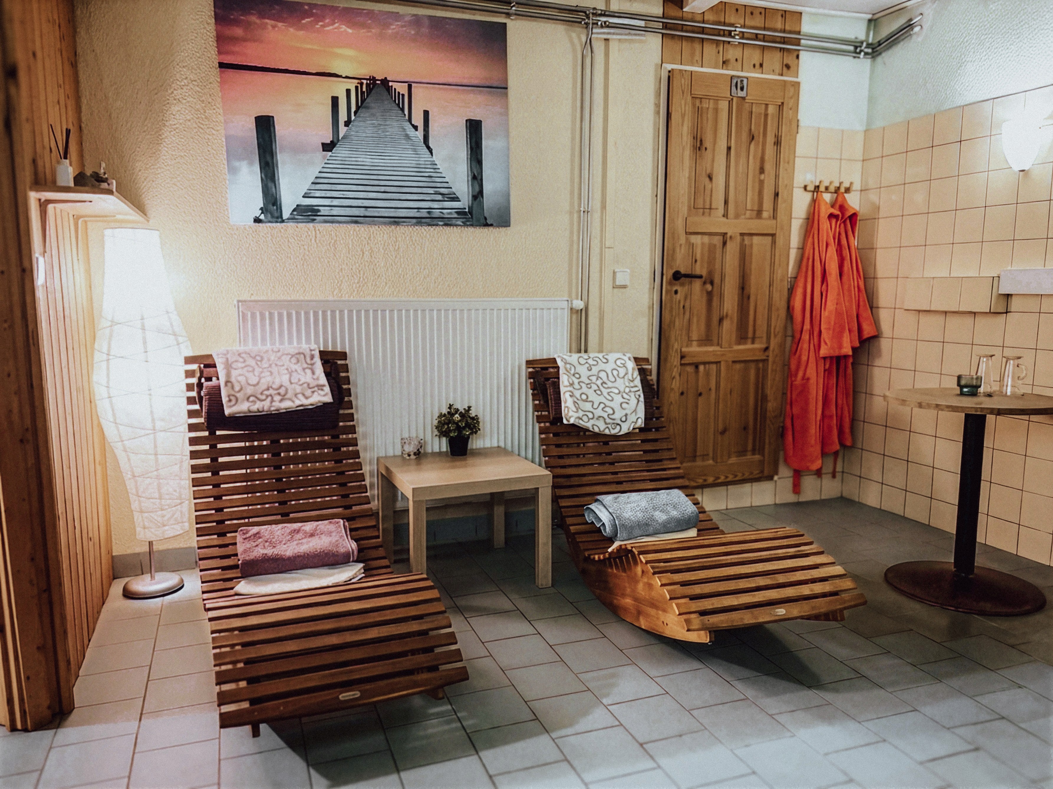 Relaxační zóna sauny — dřevěná lehátka s ručníky a polštáři, tlumené světlo, dřevěný obklad