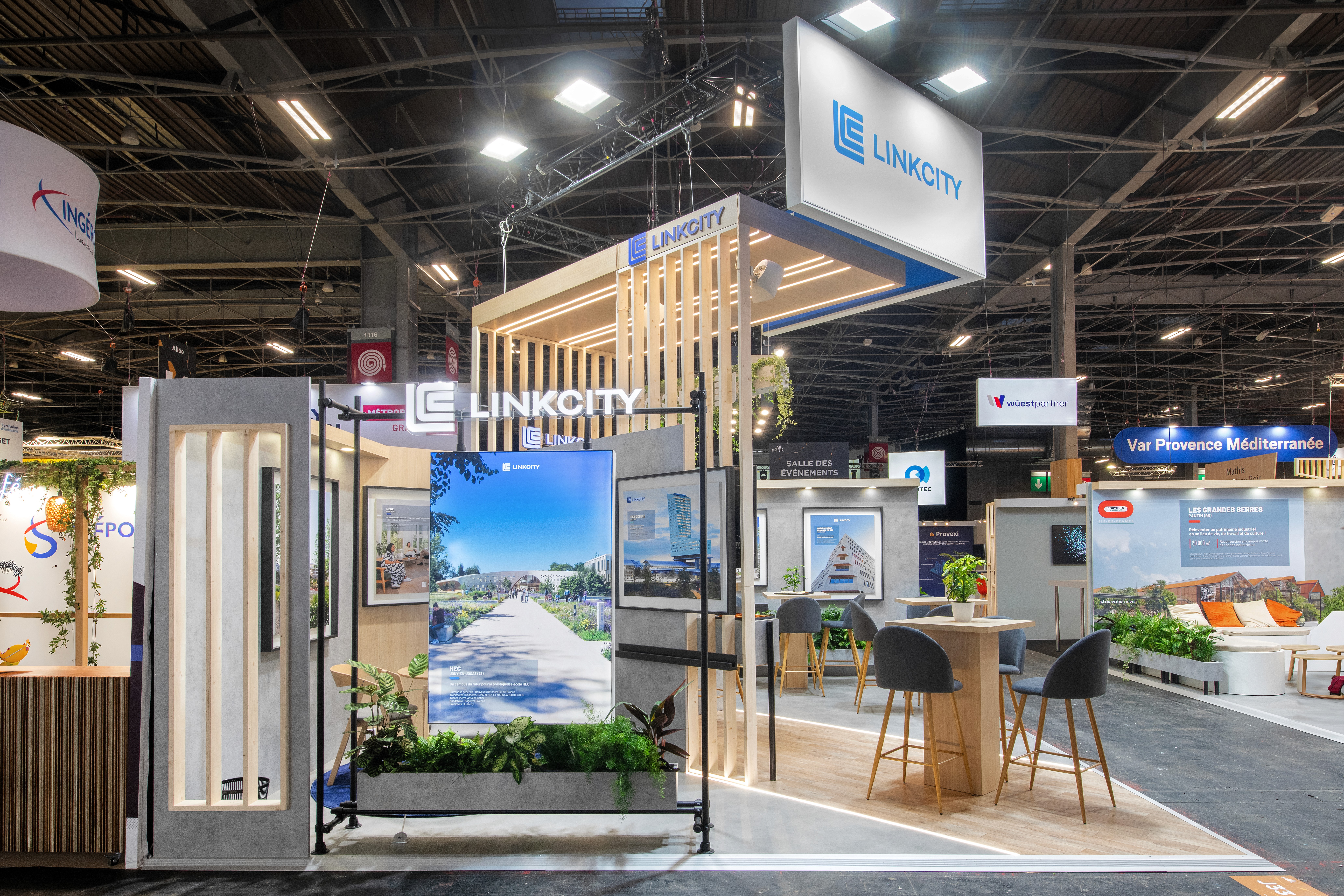 Stand Linkcity Groupe Bouygues SIMI 2025 Paris conçu par Expace – vue trois quarts du stand avec structure bois aérienne, végétation intégrée et espace d'échange promoteur immobilier professionnel