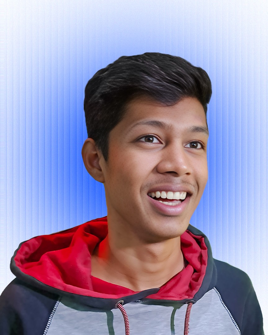 Smiling man in a blue beanie and black hoodie against a brick wall, exuding a joyful and relaxed vibe.