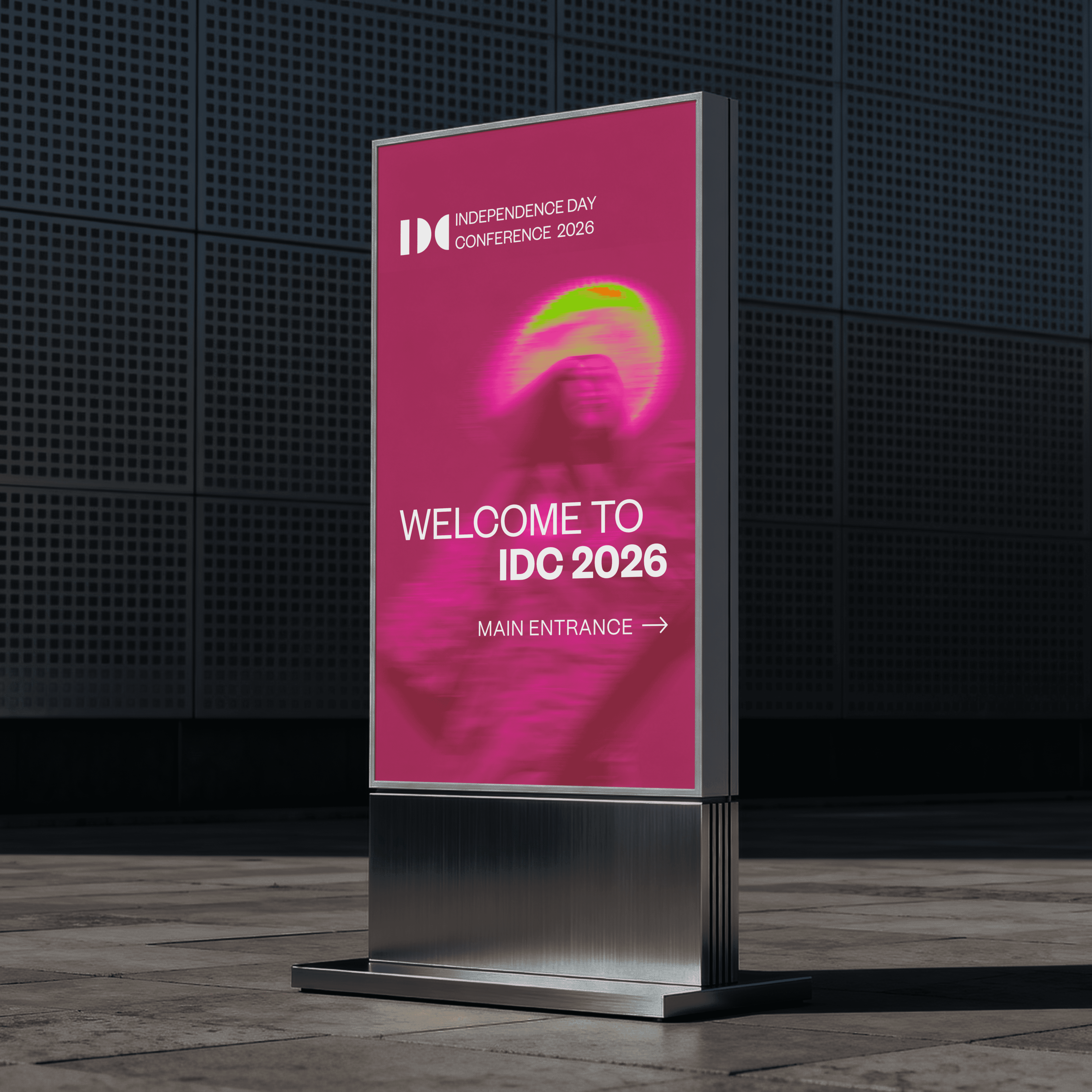 Tall freestanding display in a dark exhibition hall showing IDC 2026 branding and "Welcome to IDC 2026 — Main Entrance" wayfinding