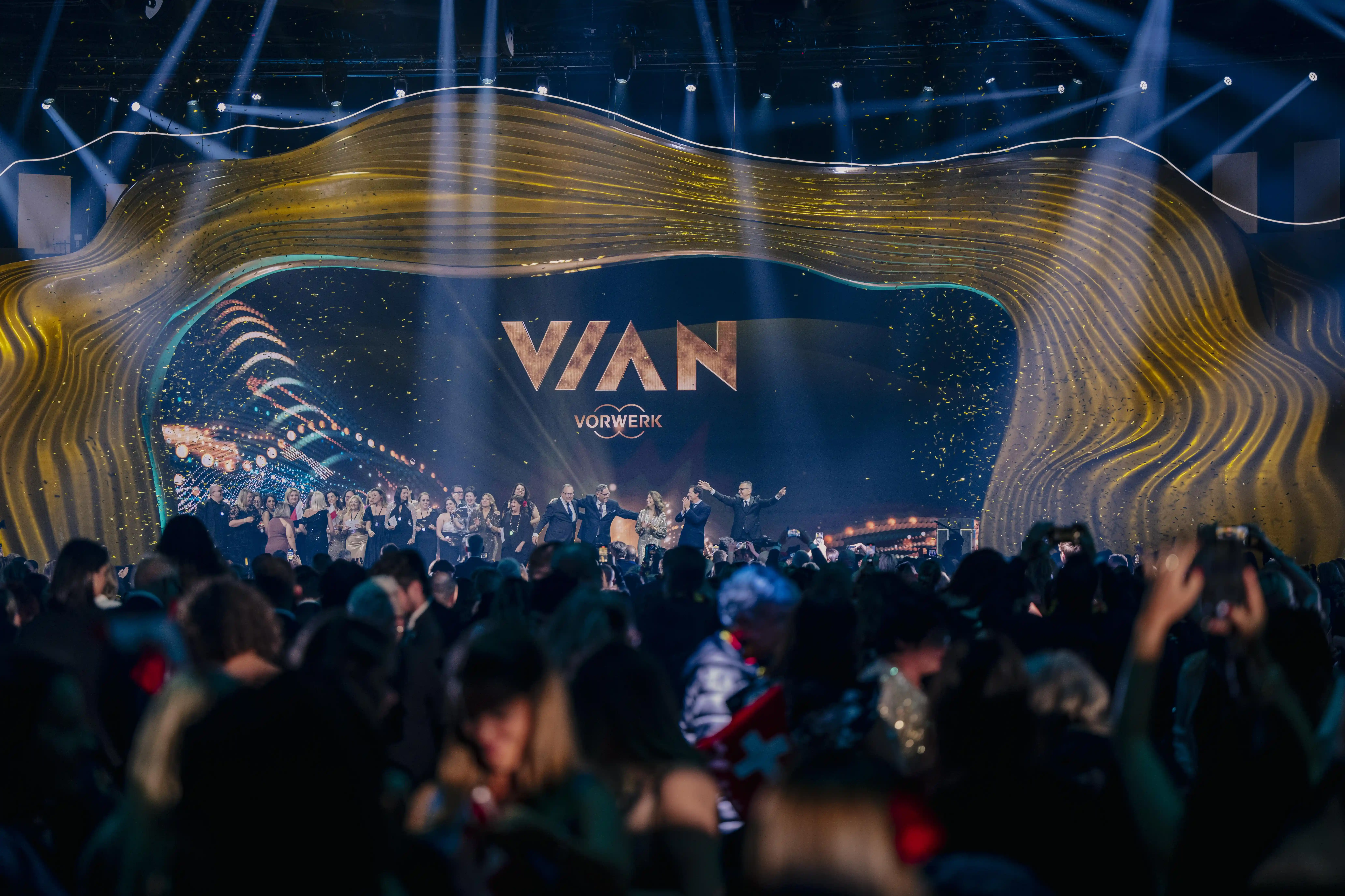 Crowd in front of the Vian stage with golden wave frame and confetti rain at the finale.