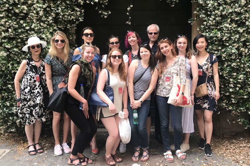 A photo of a group of people standing near a hedge.