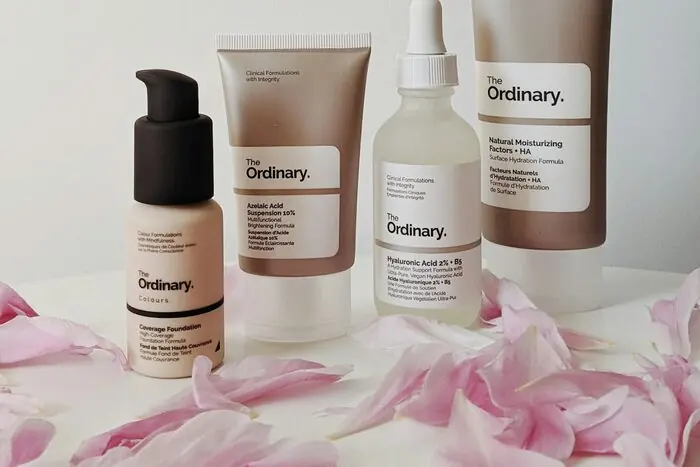 A lineup of minimalist skincare bottles and droppers on a pale beige surface