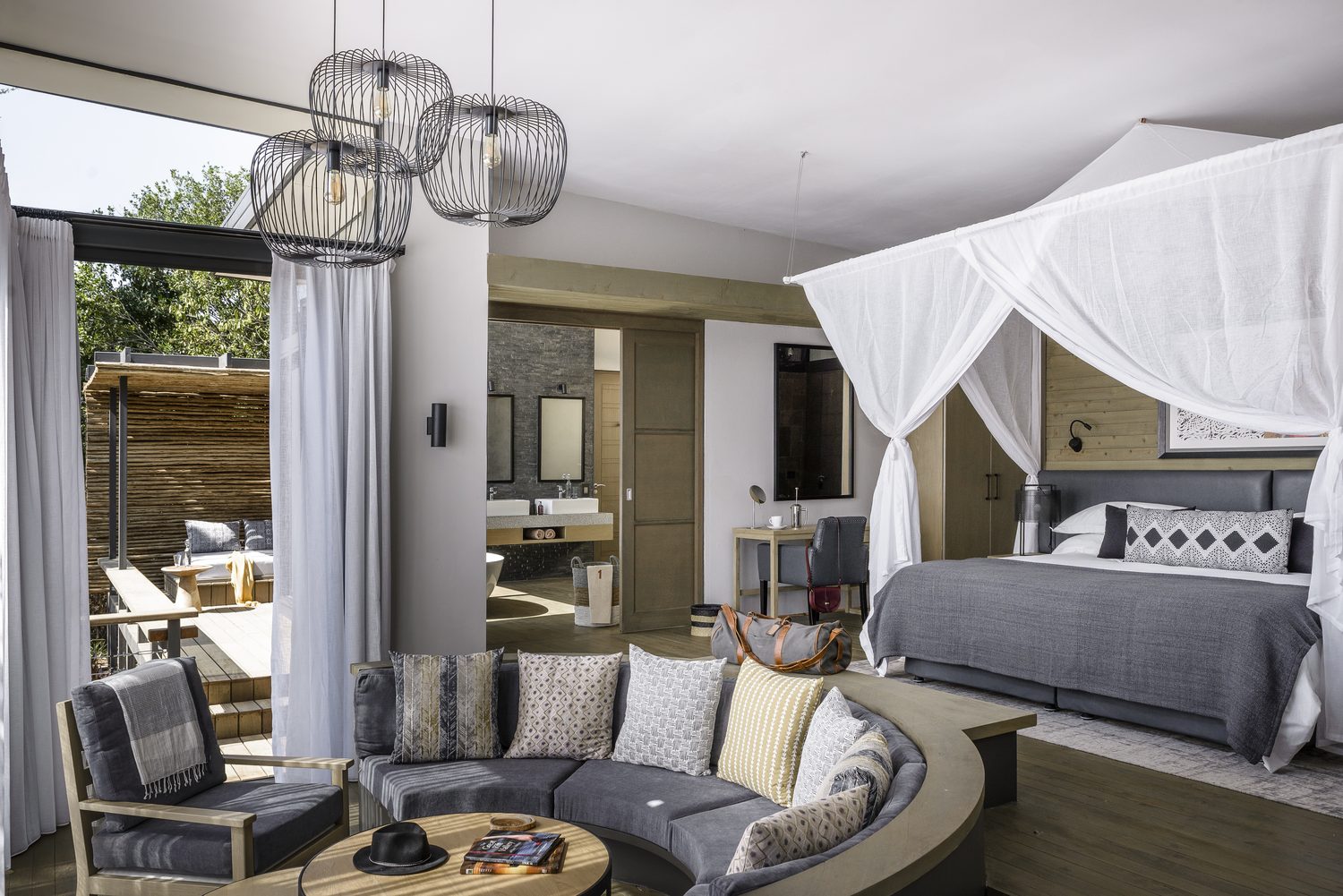 A canopied lodge suite in soft greys opening to a private patio