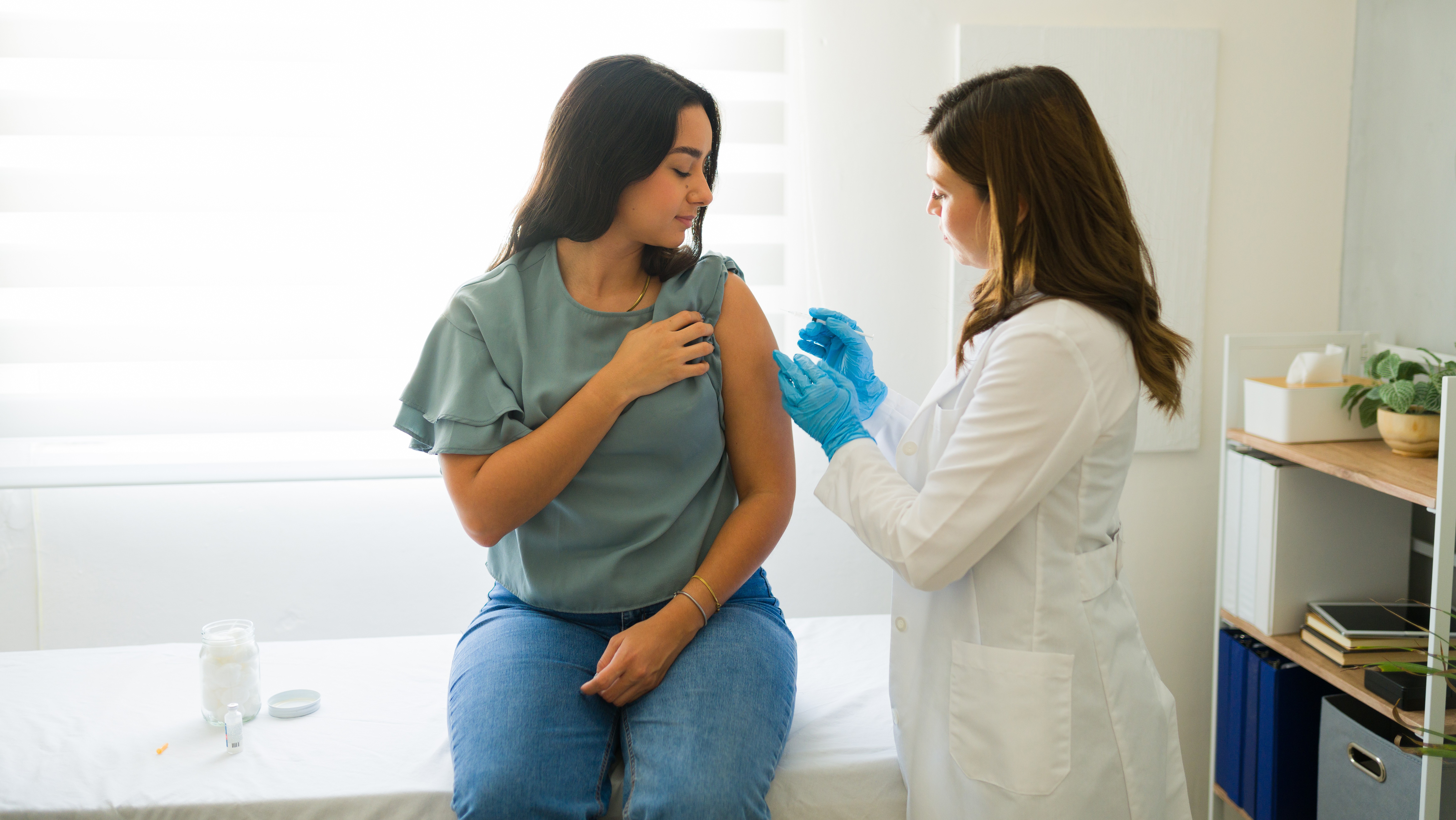 A female medic giving a female patient a medical shot in the arm.
