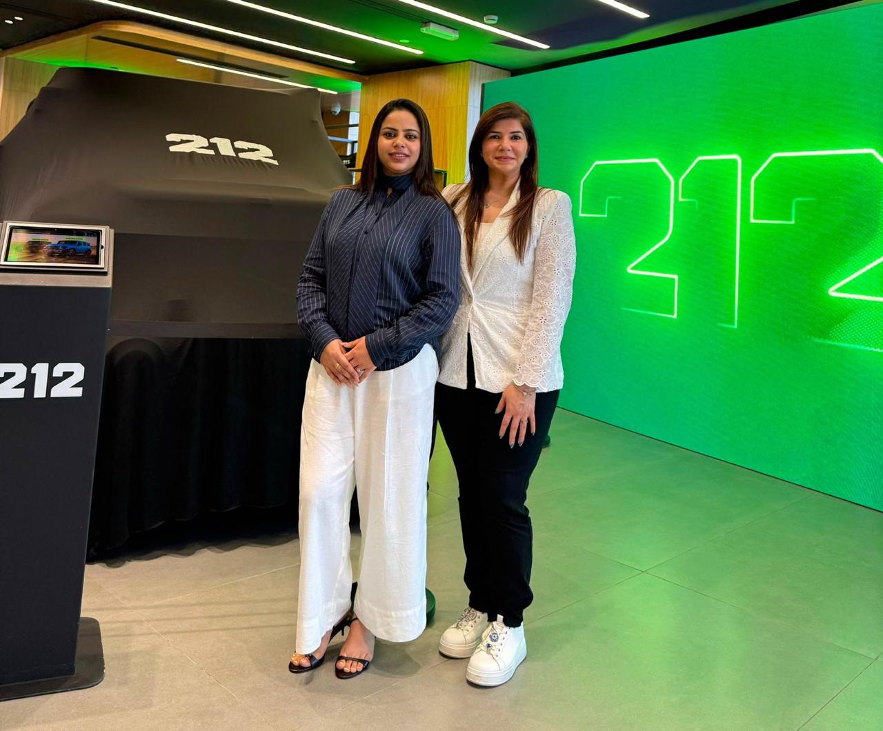 Two women inside a green exhibition booth