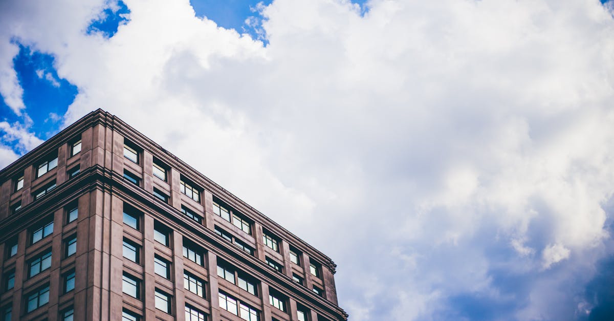 A low angle view of a modern building set against a dynamic cloudy sky.