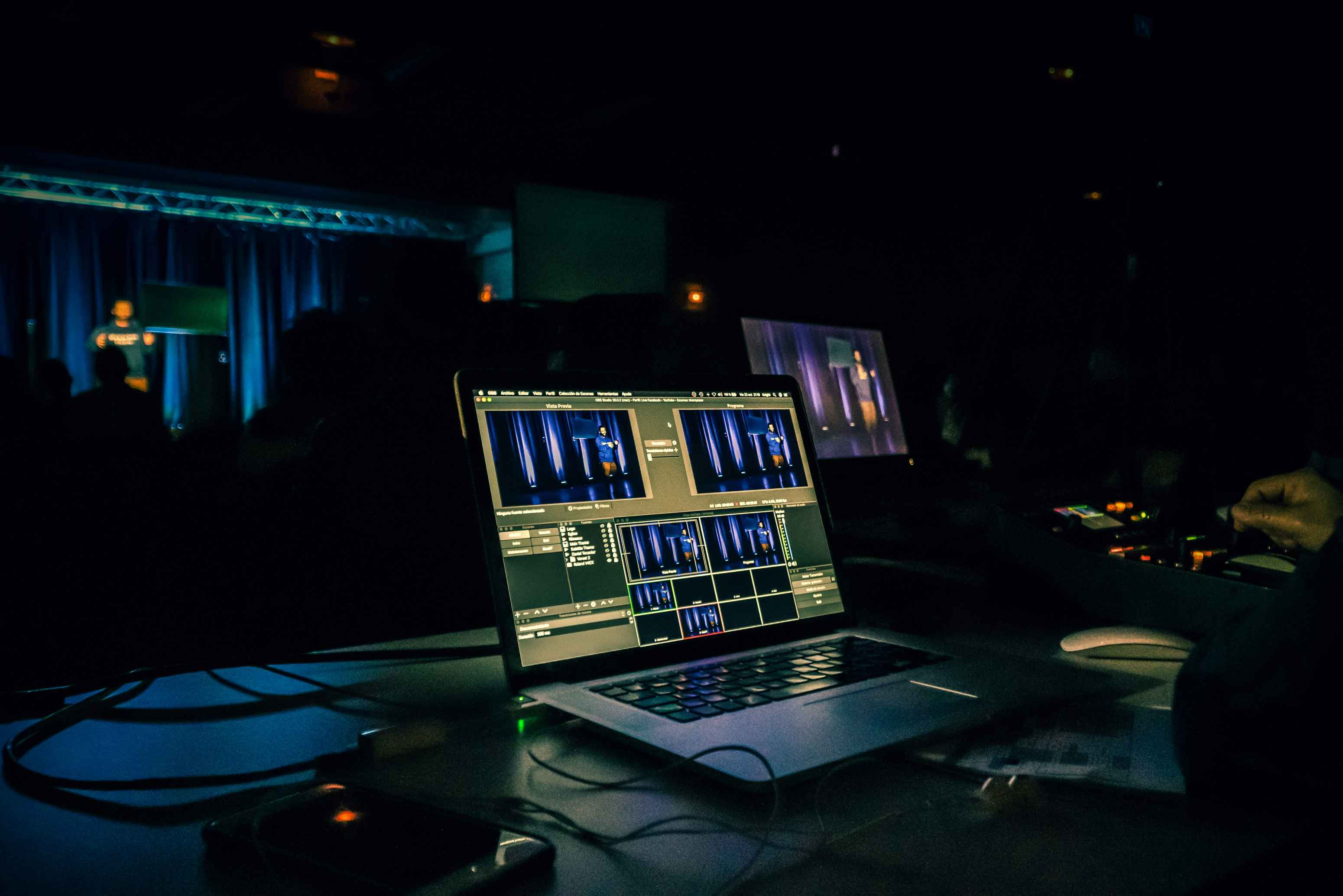 Live event video editing setup with laptop and control panel in a dark venue