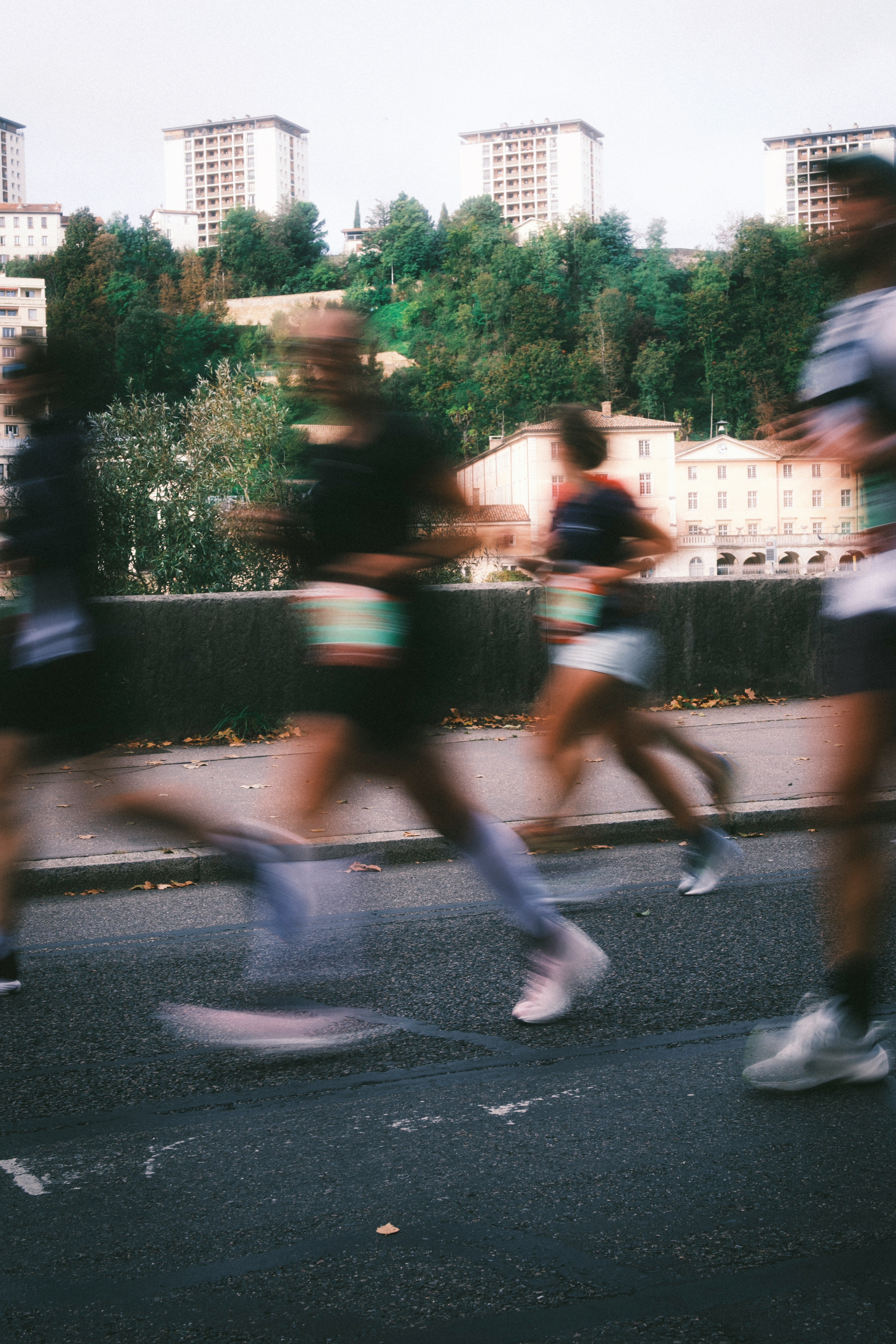 Runners race on a street with buildings behind.