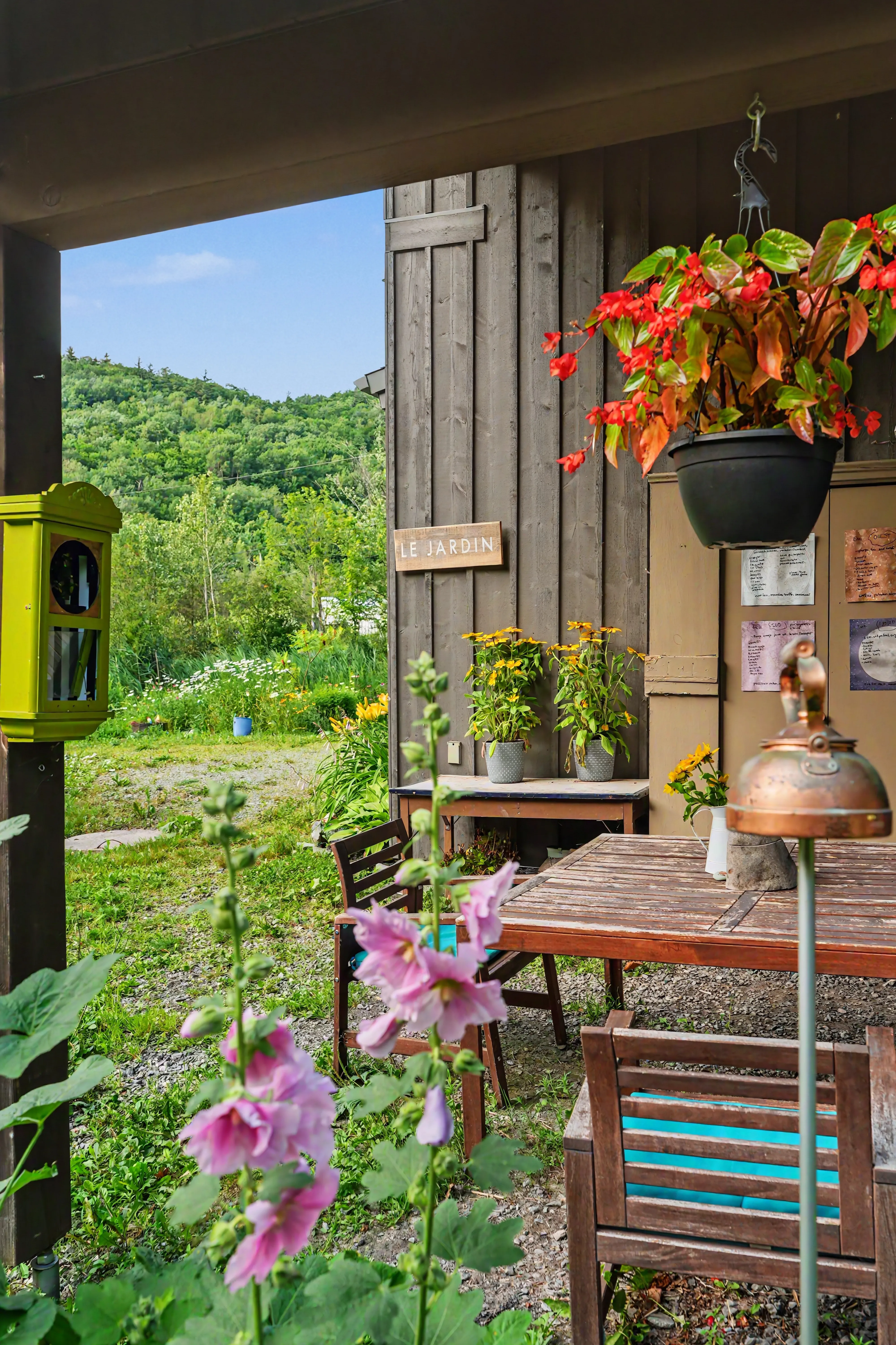 Garden of the R112 North cottage in Austin, with a view of the lush green mountains under a blue sky dotted with clouds, wooden sign "The Garden" in the foreground.