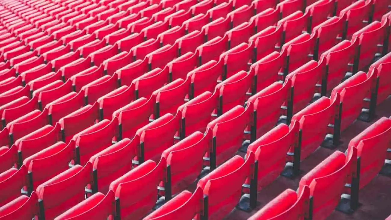 Red stadium seats, perfect seating for spectators at football tournaments, an empty stadium area symbolising the preparations for a major tournament with CoachingArea.