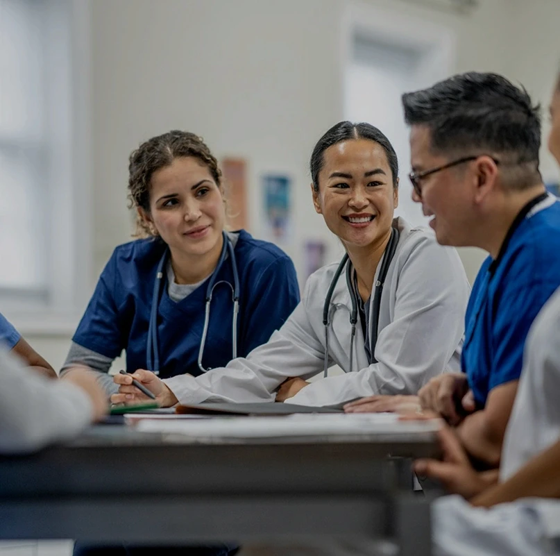 Group of medical students and healthcare professionals collaborating around a table in a classroom setting