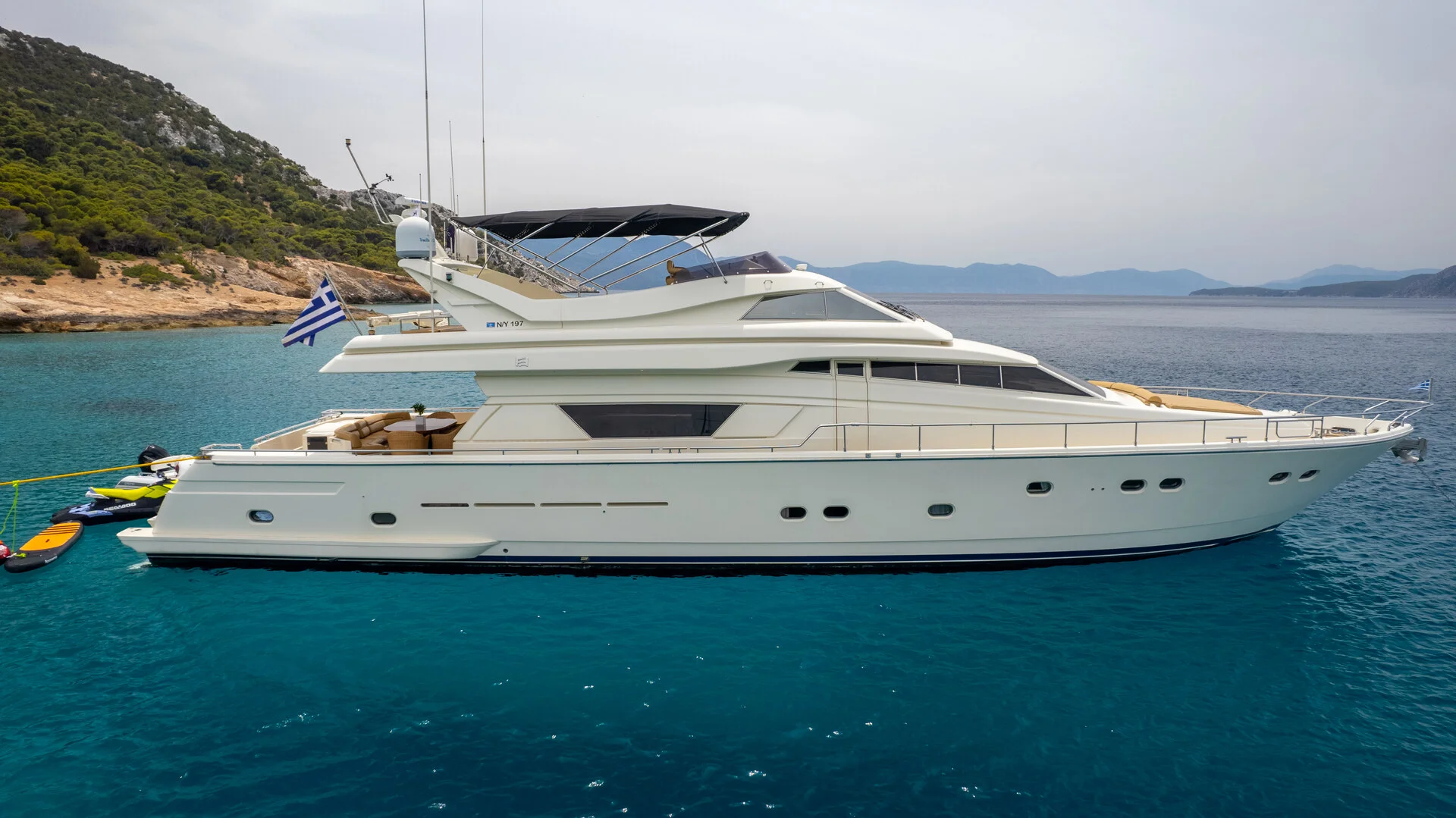 White Rock 36 speedboat with captain at helm cruising calm blue waters near Paros coastline with hills in background.