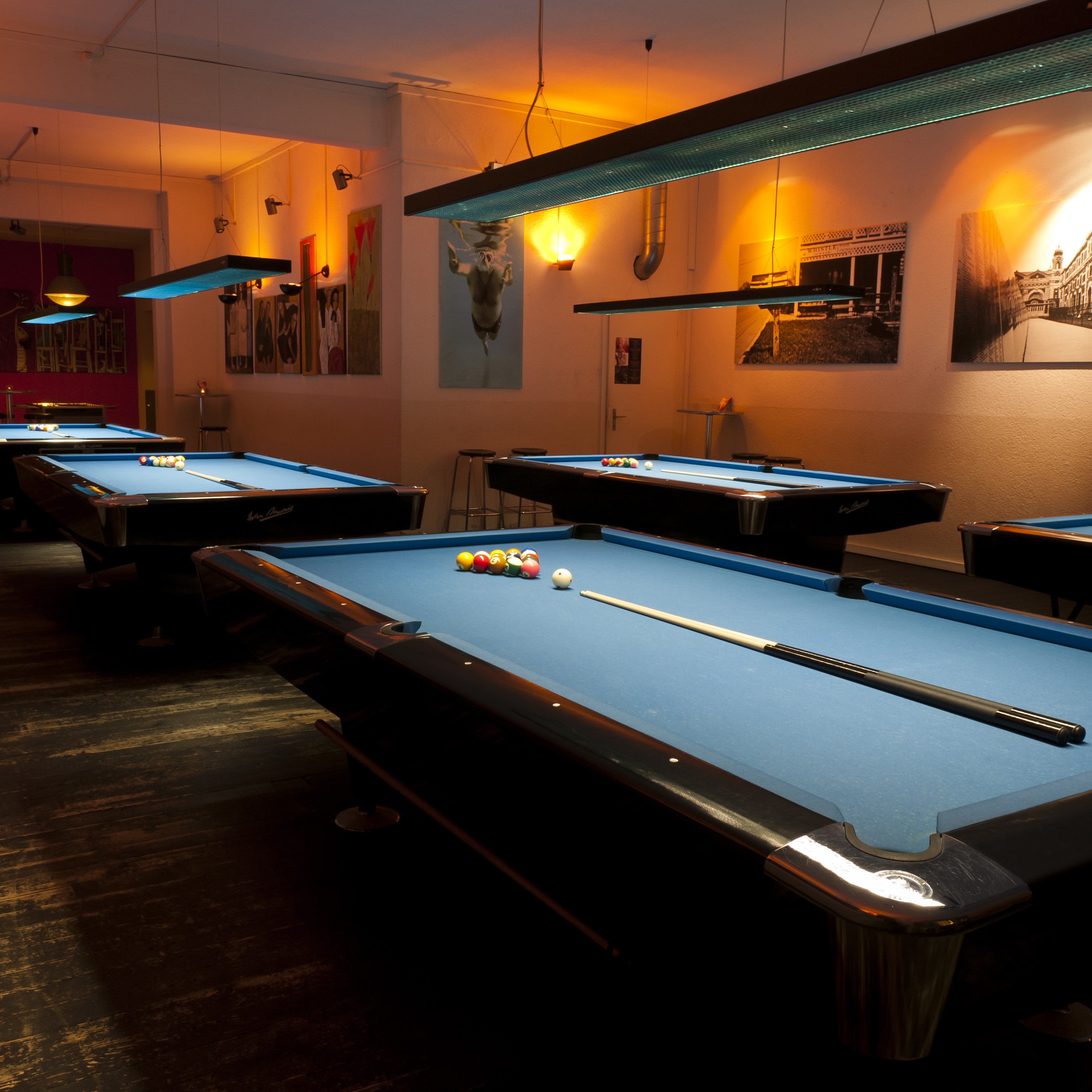 Vier Billardtische mit blauem Tuch im Spielbereich