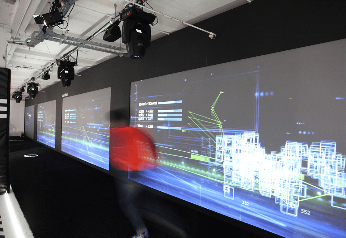 Modern gallery with interactive digital displays showcasing dynamic, futuristic data visualizations projected onto dark walls, featuring a person in motion, creating a blend of technology and art.