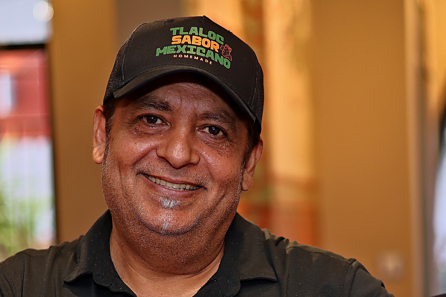 Close-up of the brand logo on the front of a black trucker cap, printed three and a half inches wide