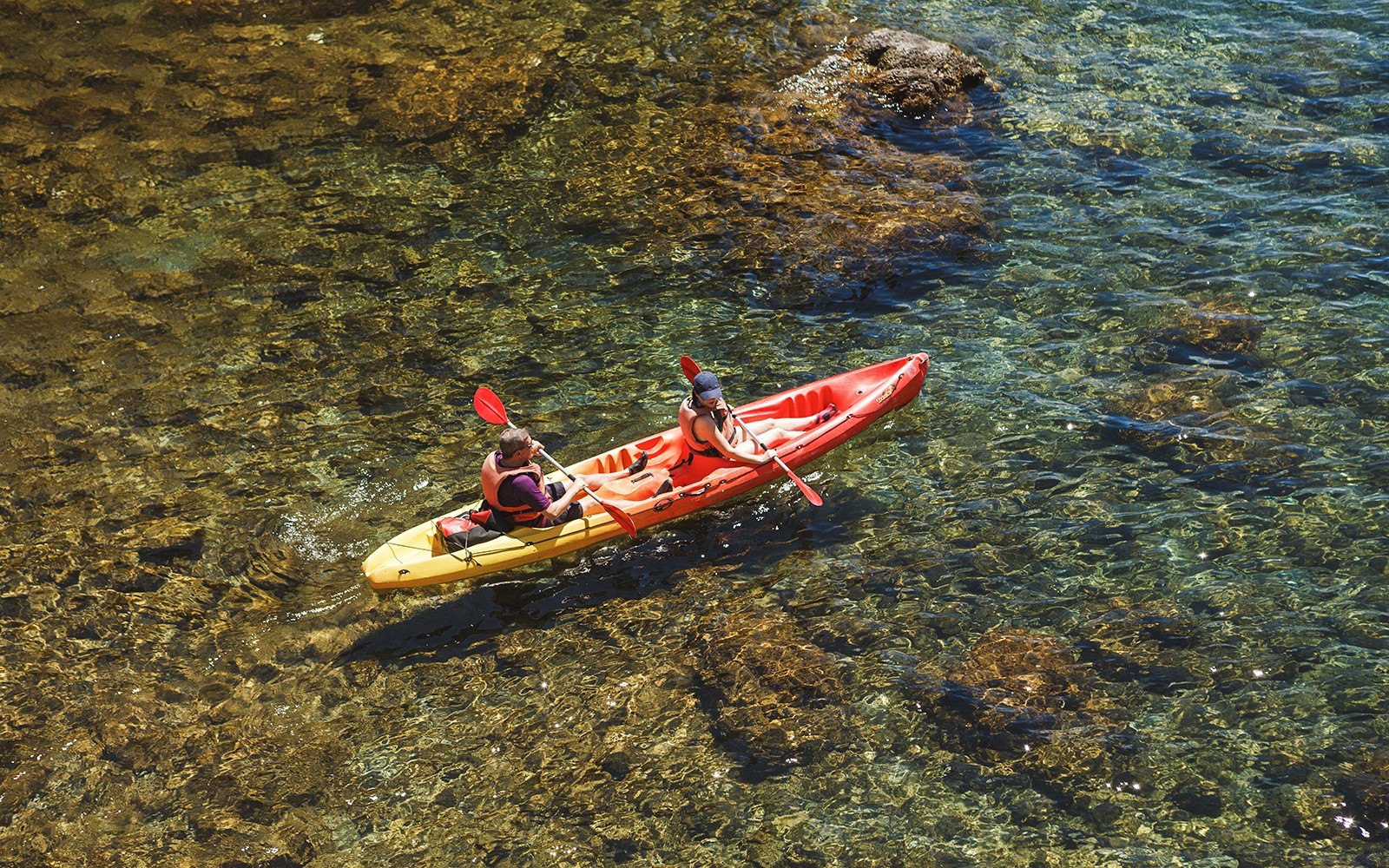 Kayakers paddling in clear waters near Dubrovnik at sunset.