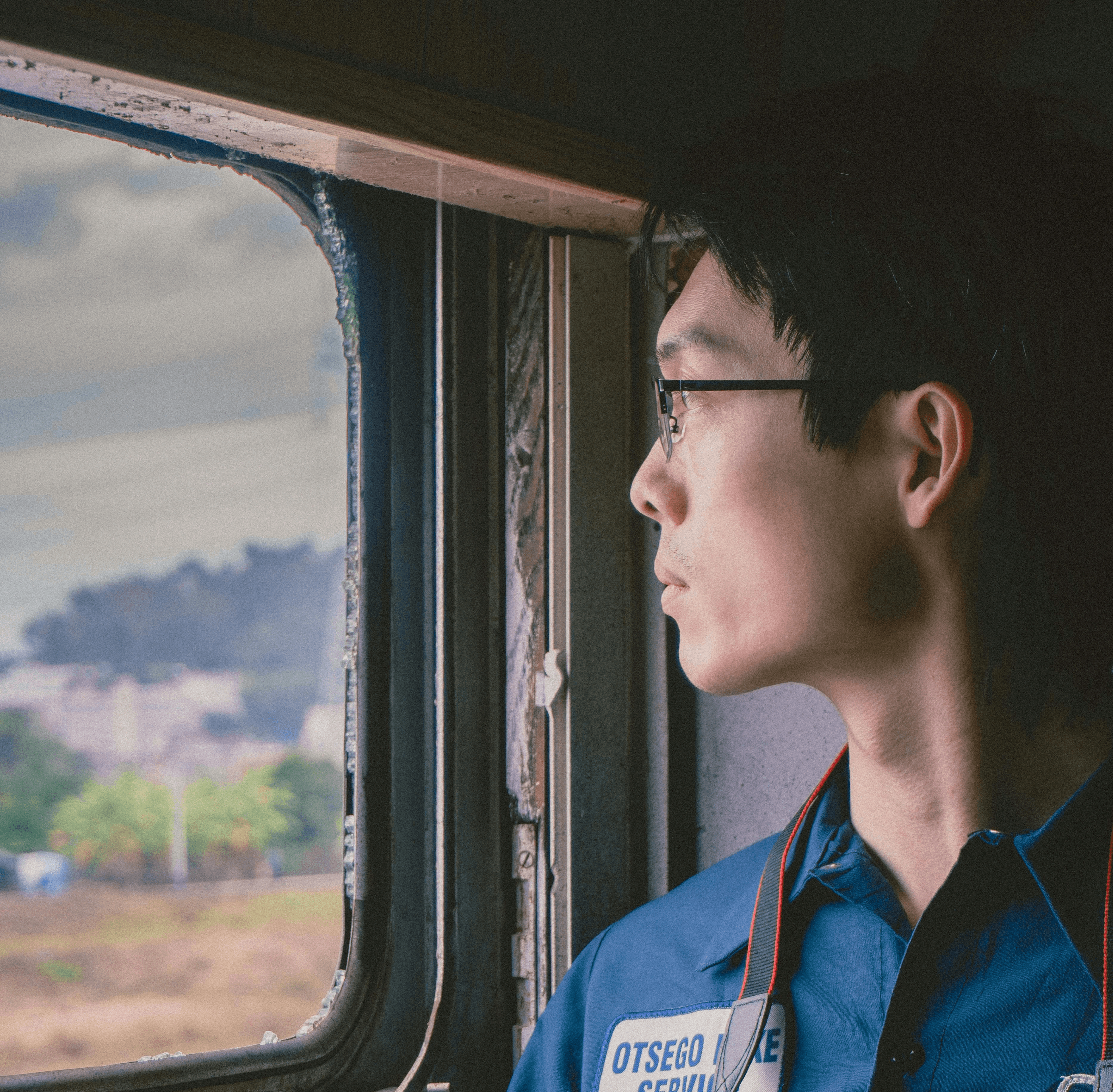 Close-up of a woman's serene face in warm lighting, eyes gazing upward, highlighting her soft expression and textured skin. Mood is calm and contemplative.