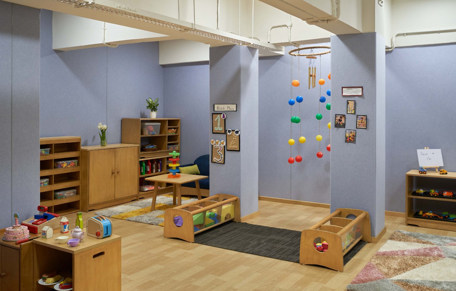 Nature-inspired preschool entrance with sculptural tree partitions and suspended green leaf ceiling panels.
