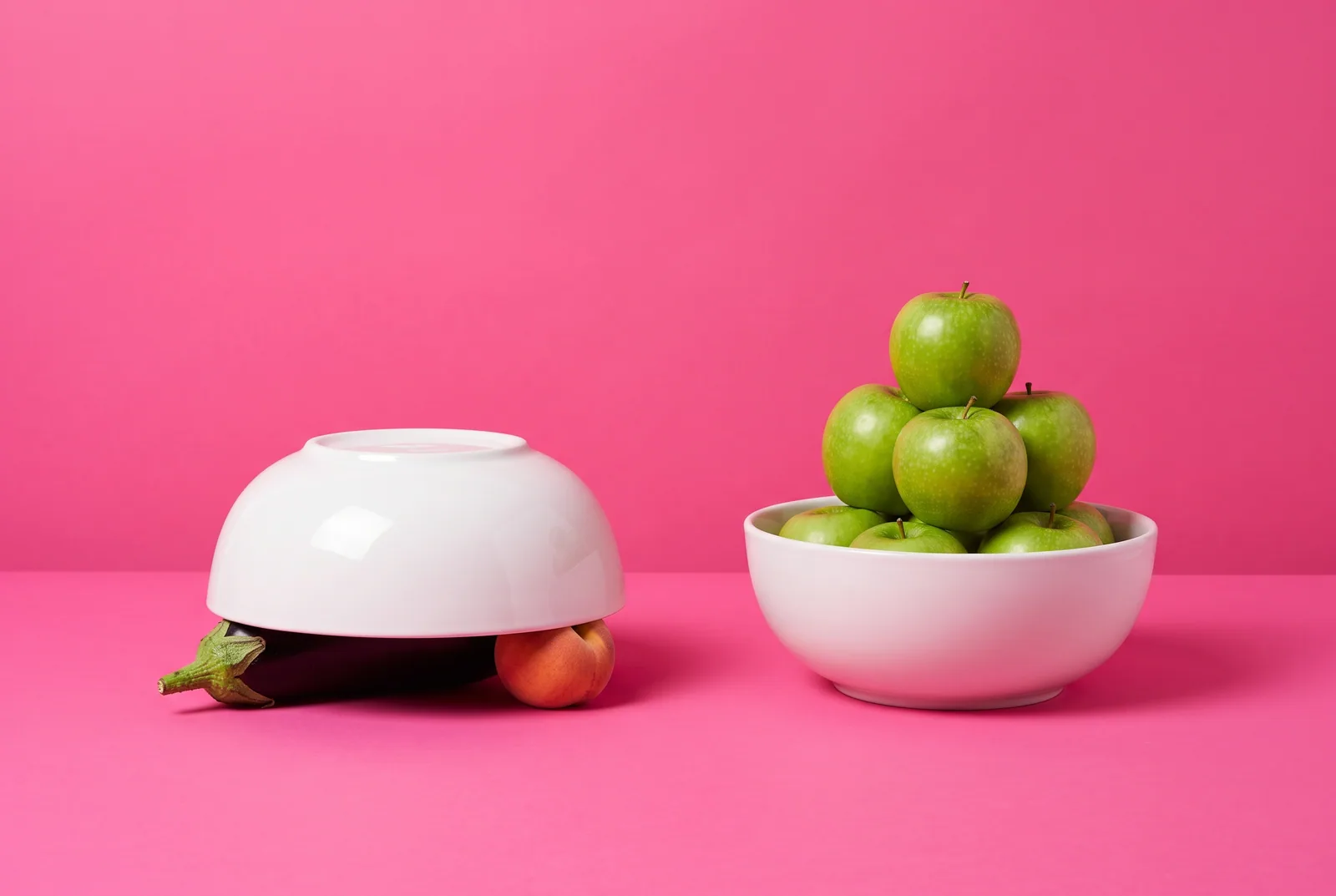 Upturned white bowl covering peaches and an eggplant on a hot pink backdrop, illustrating how to block NSFW subreddits by muting them