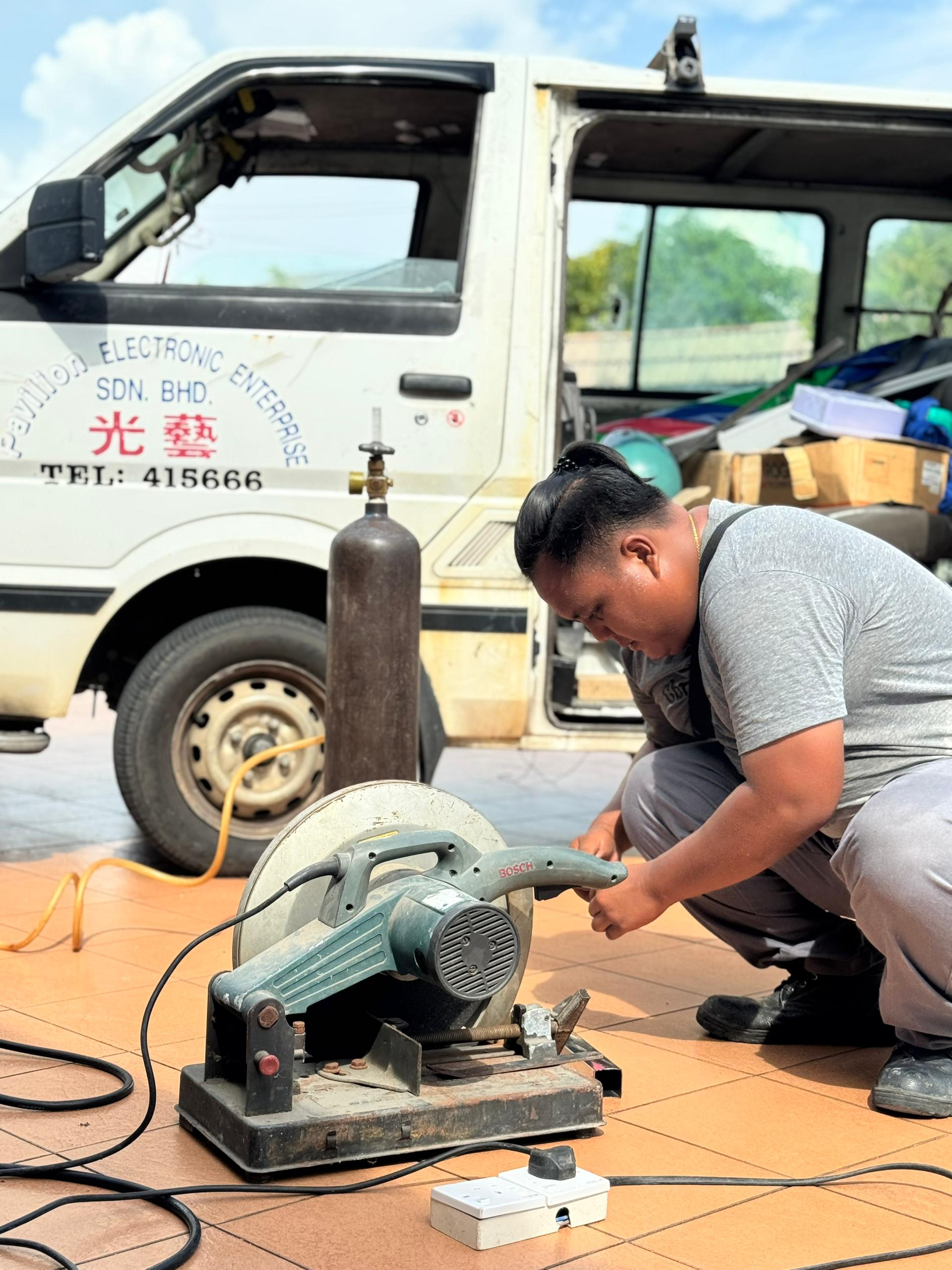 Pavilion Electronic crew cutting electric fence posts to length, Miri, Sarawak