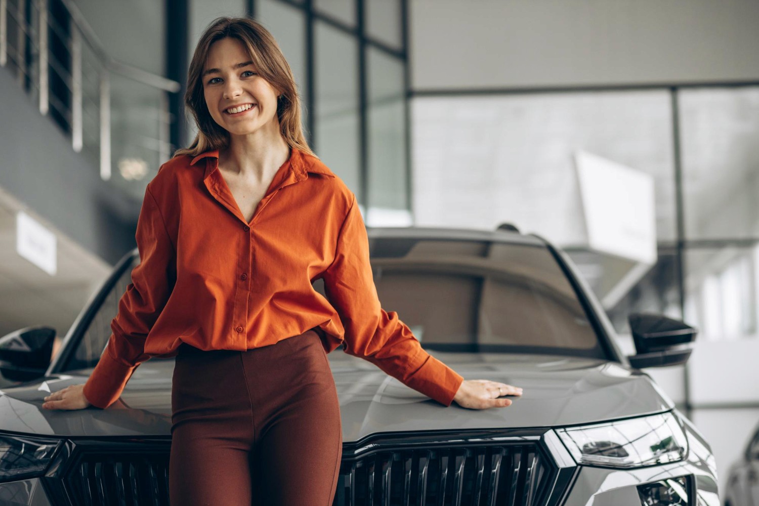Modern bathroom featuring wooden cabinetry, a bathtub, a sleek sink, and natural light from a window.