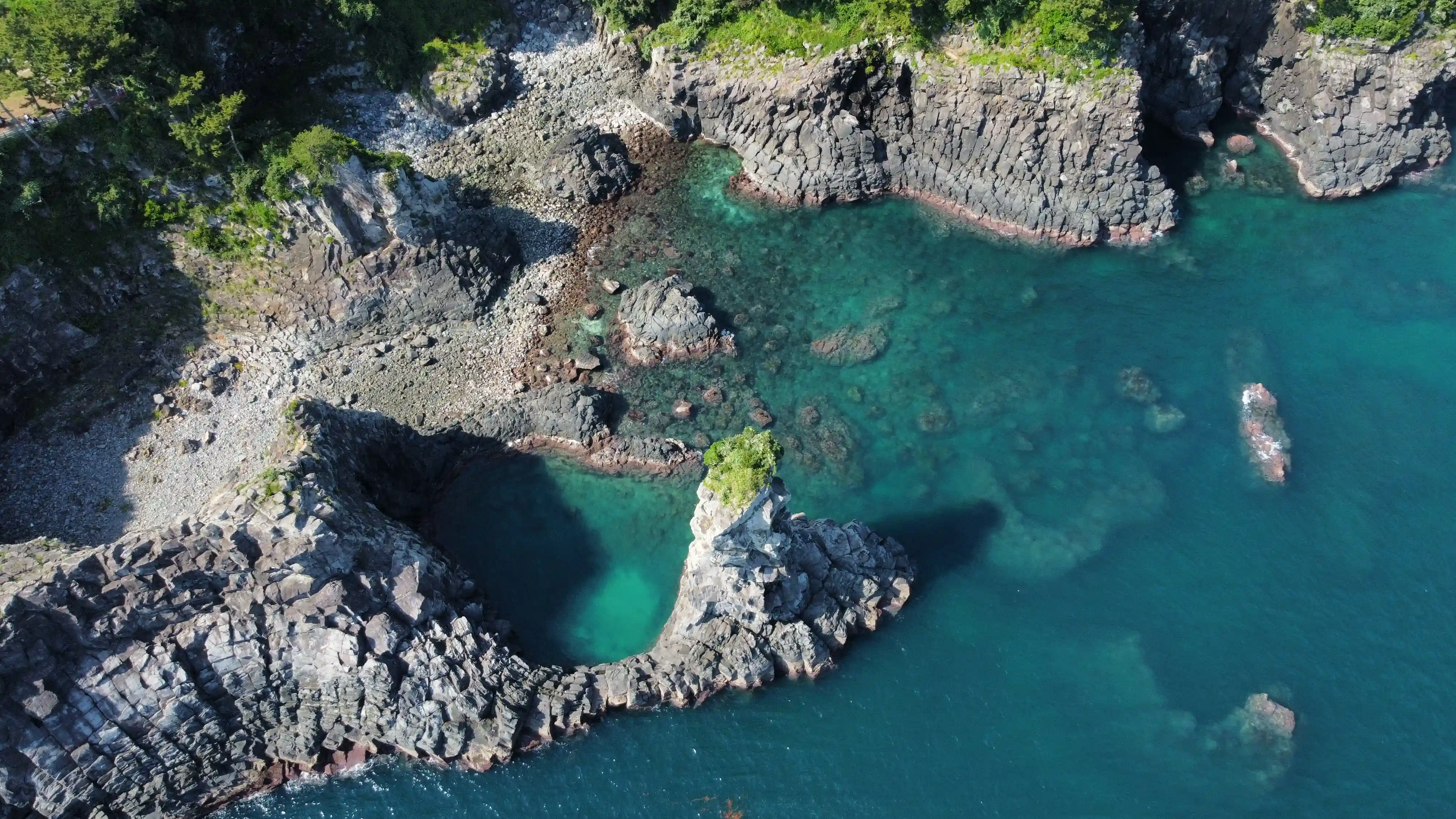 drone shot van prachtige rotsformaties en blauw water op jeju island