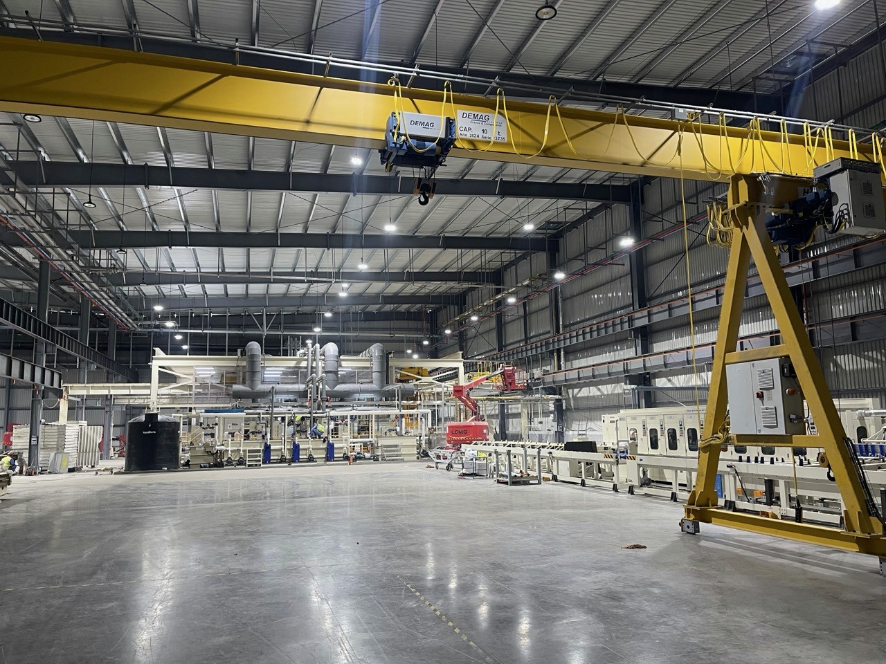 Heavy‑industry production plant with machinery equipment, bright LED ceiling lights inside factory building