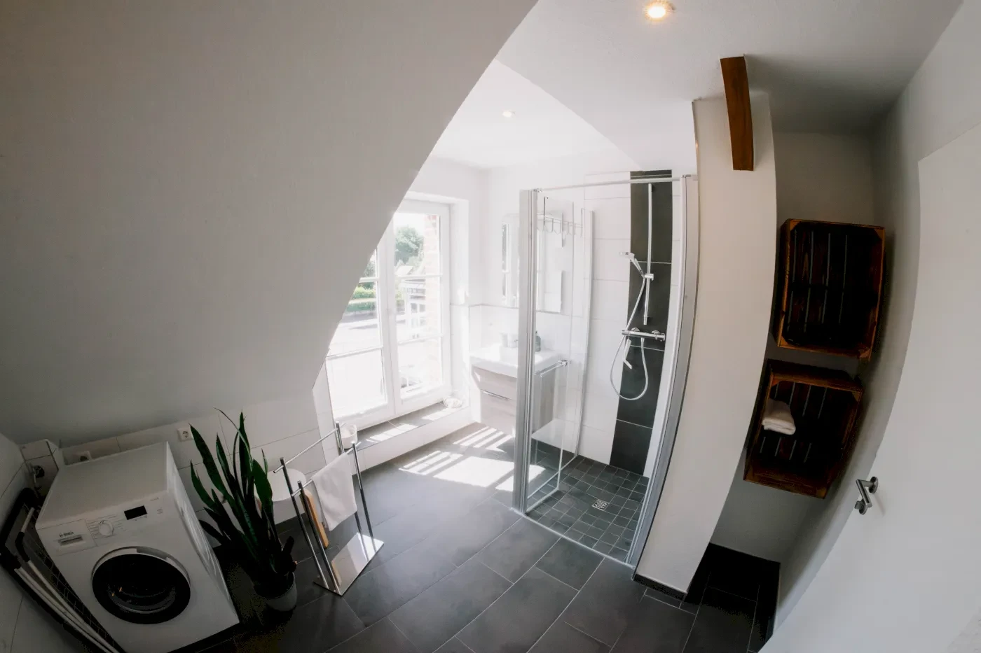 Badezimmer mit bodentiefer Dusche, Ausblick nach draußen und Waschmaschine.