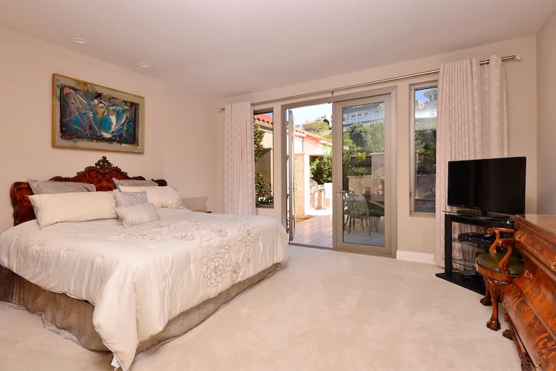 Tranquil master bedroom with balcony access and fireplace in Harbor Ridge Transitional Remodel.