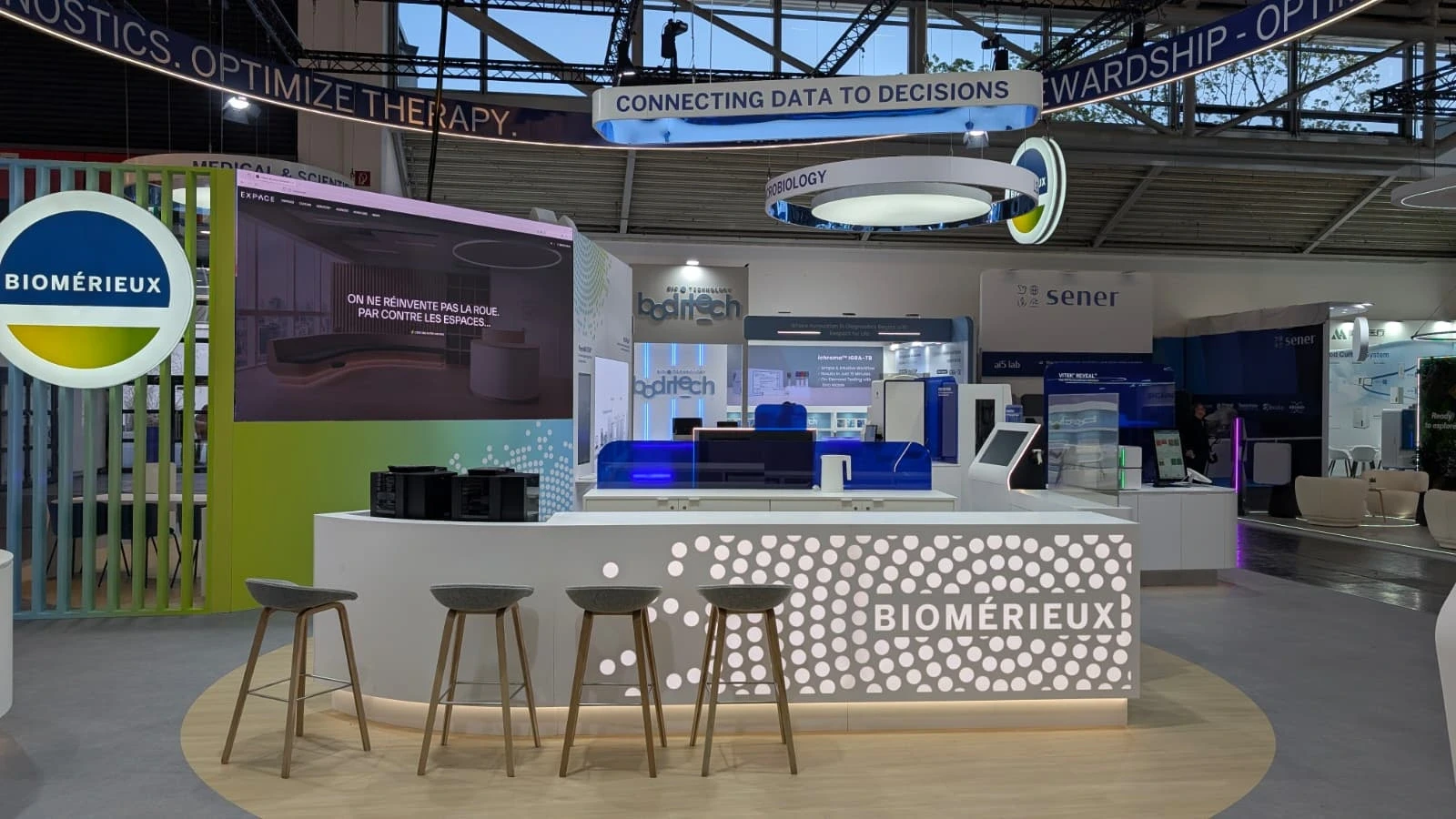 Stand bioMérieux conçu et réalisé par Expace pour le congrès ESCMID Global 2026 à Munich – stand sur-mesure de diagnostic médical avec anneaux lumineux, comptoirs d'accueil et espaces de démonstration.