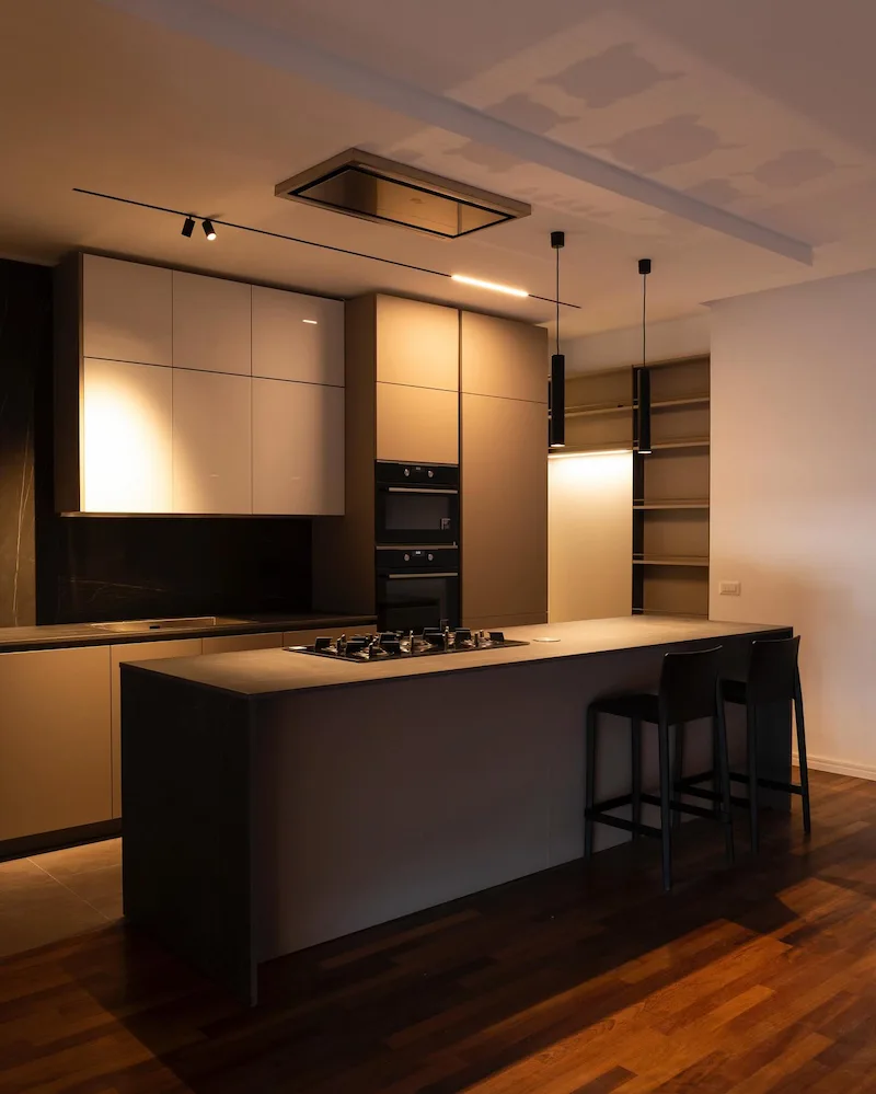 cucina di lusso nero lucido con soffitti a più volumi e con pendant luci soffuse su penisola