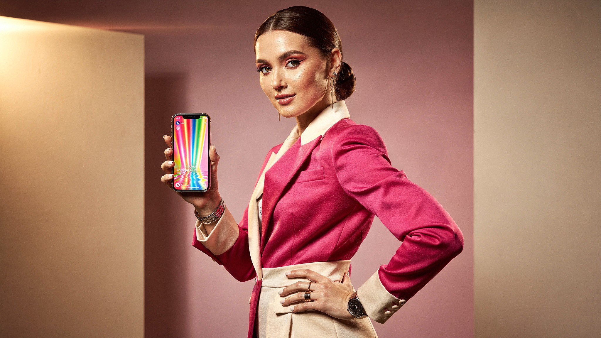 Creator holding her phone showing a vertical video in a pink studio