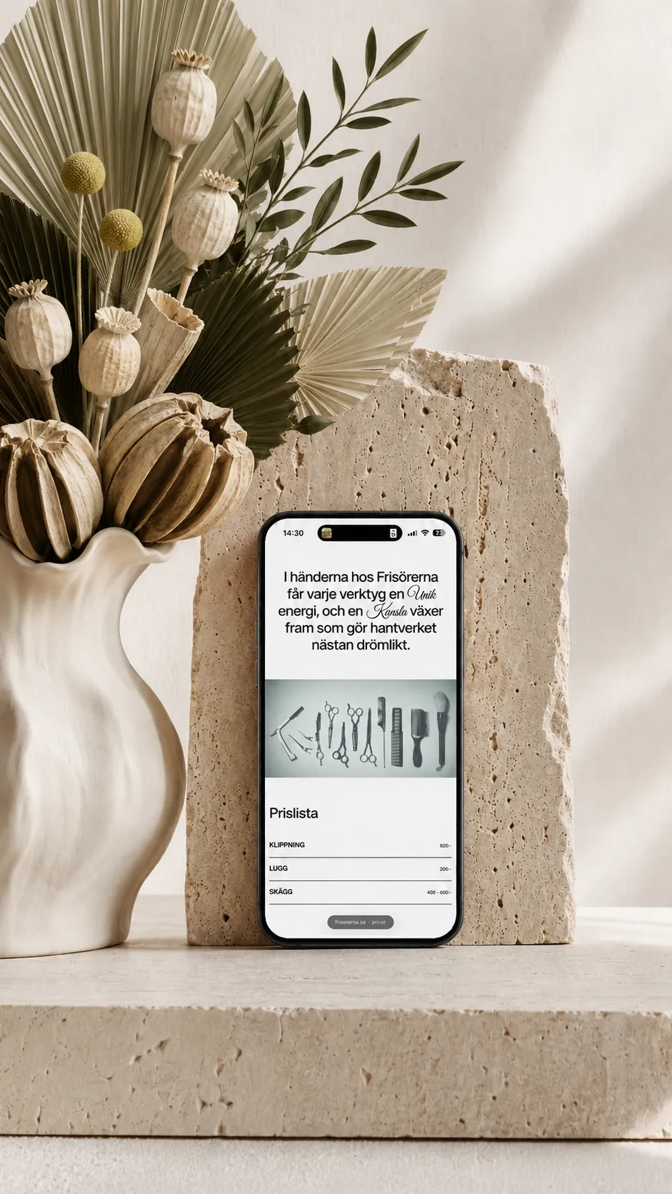 iPhone displaying the Frisörerna price list, styled with sculptural green foliage, ivory seed pods and a travertine stone support.