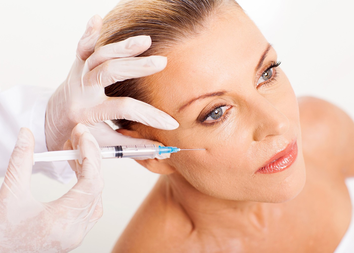Close-up of forehead injection for preventative Botox in a bright, sterile treatment room.