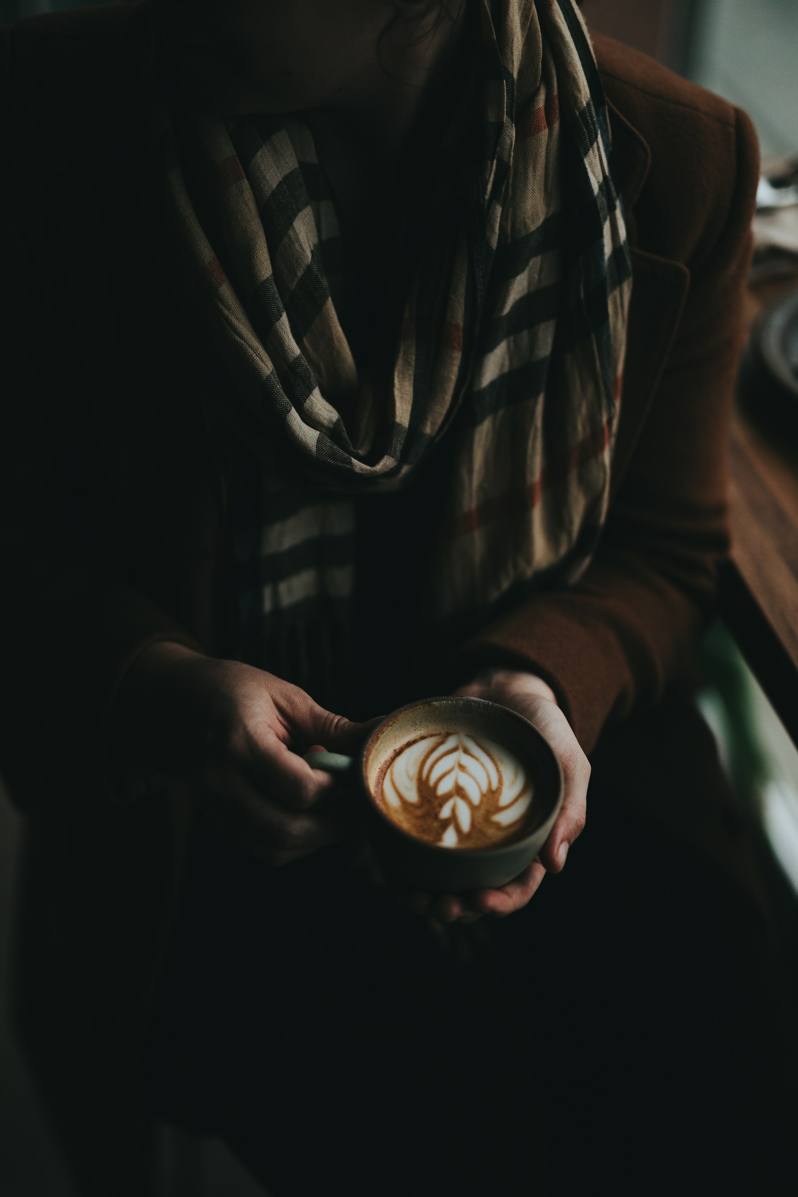 Persona sosteniendo una taza con arte latte en una cafetería de especialidad