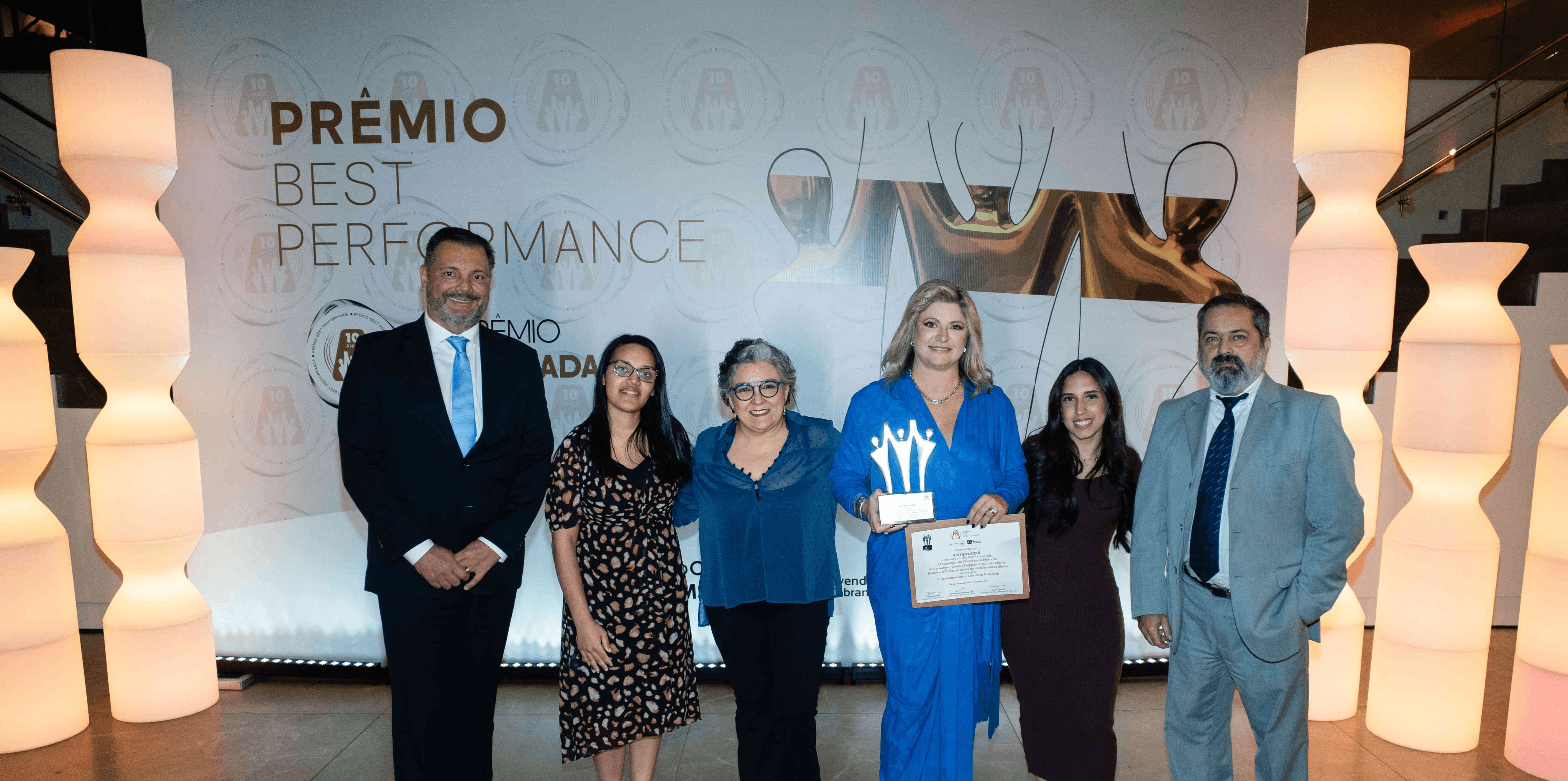 Executivos da vemproazul posando com troféu prata e certificado no palco do Prêmio Best Performance 2025