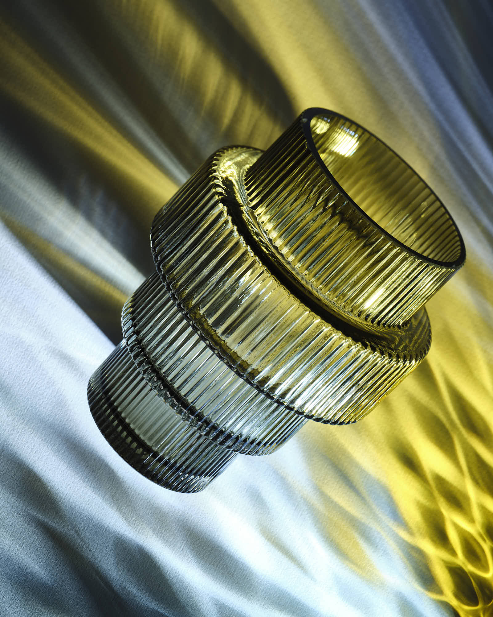 Abstract glass artwork with ribbed texture and dynamic lighting on a blue and yellow background.