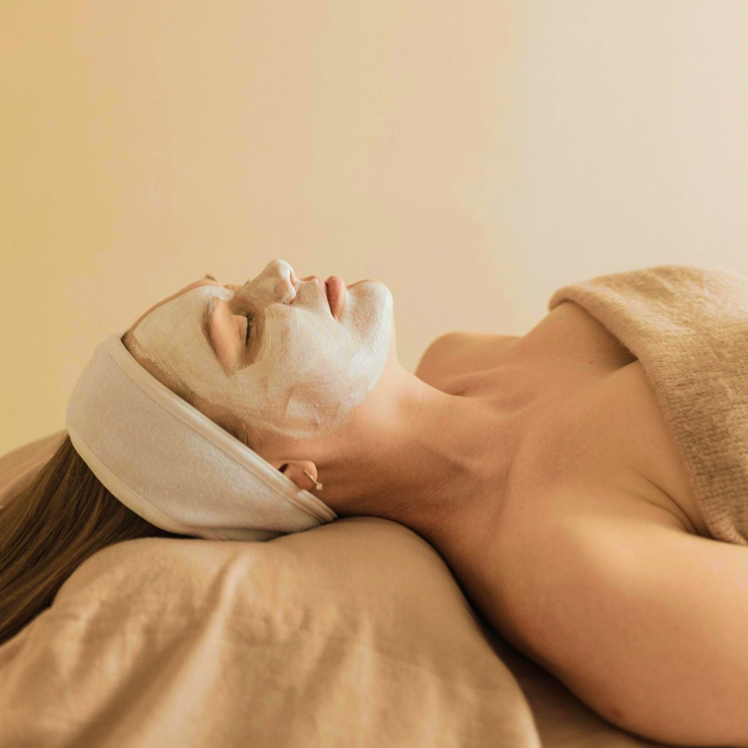 Woman lying on a bed with a painted face mask