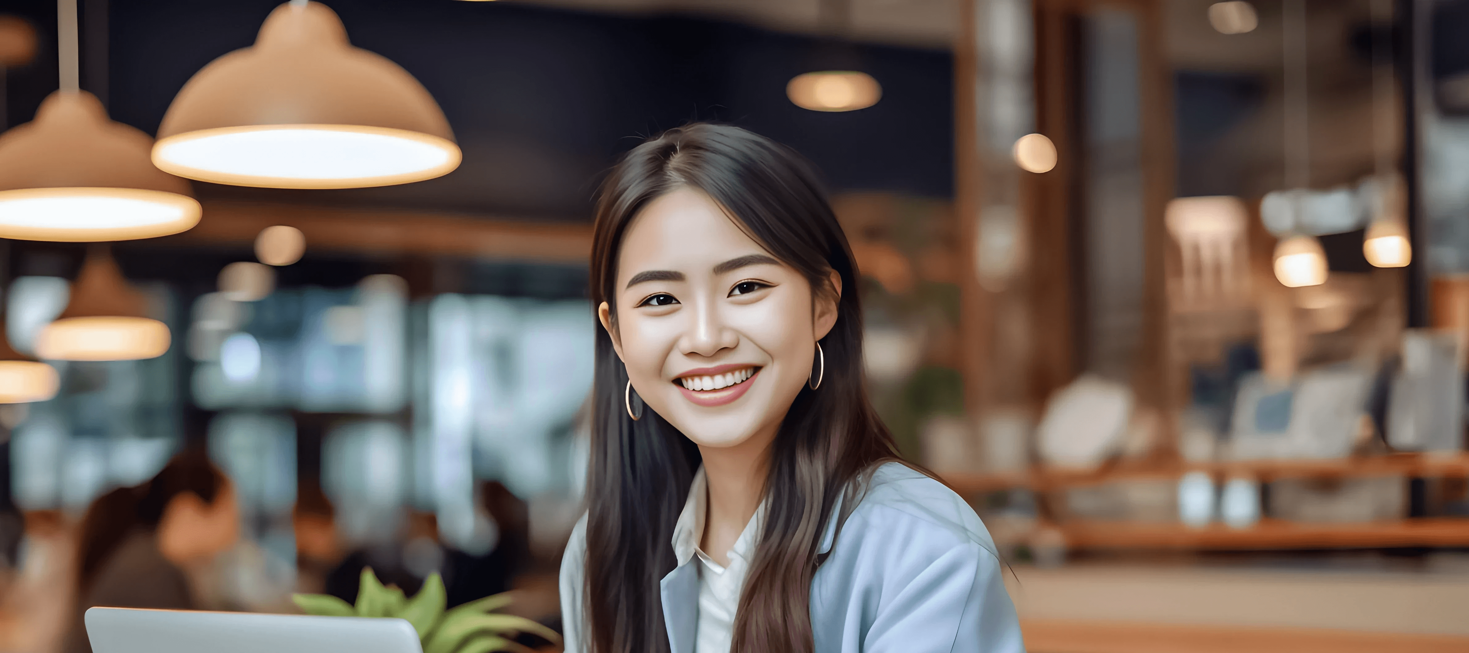 Headshot of Tiffany, a smiling young professional woman working on a laptop in a cafe.