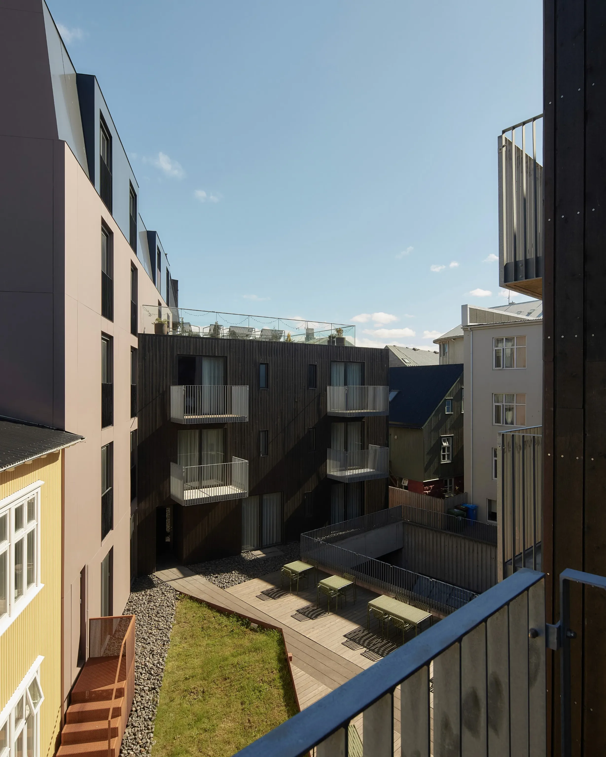Sunlit view across Exeter Hotel’s courtyard and surrounding buildings, with rooftop seating, balconies, and a bright blue sky.